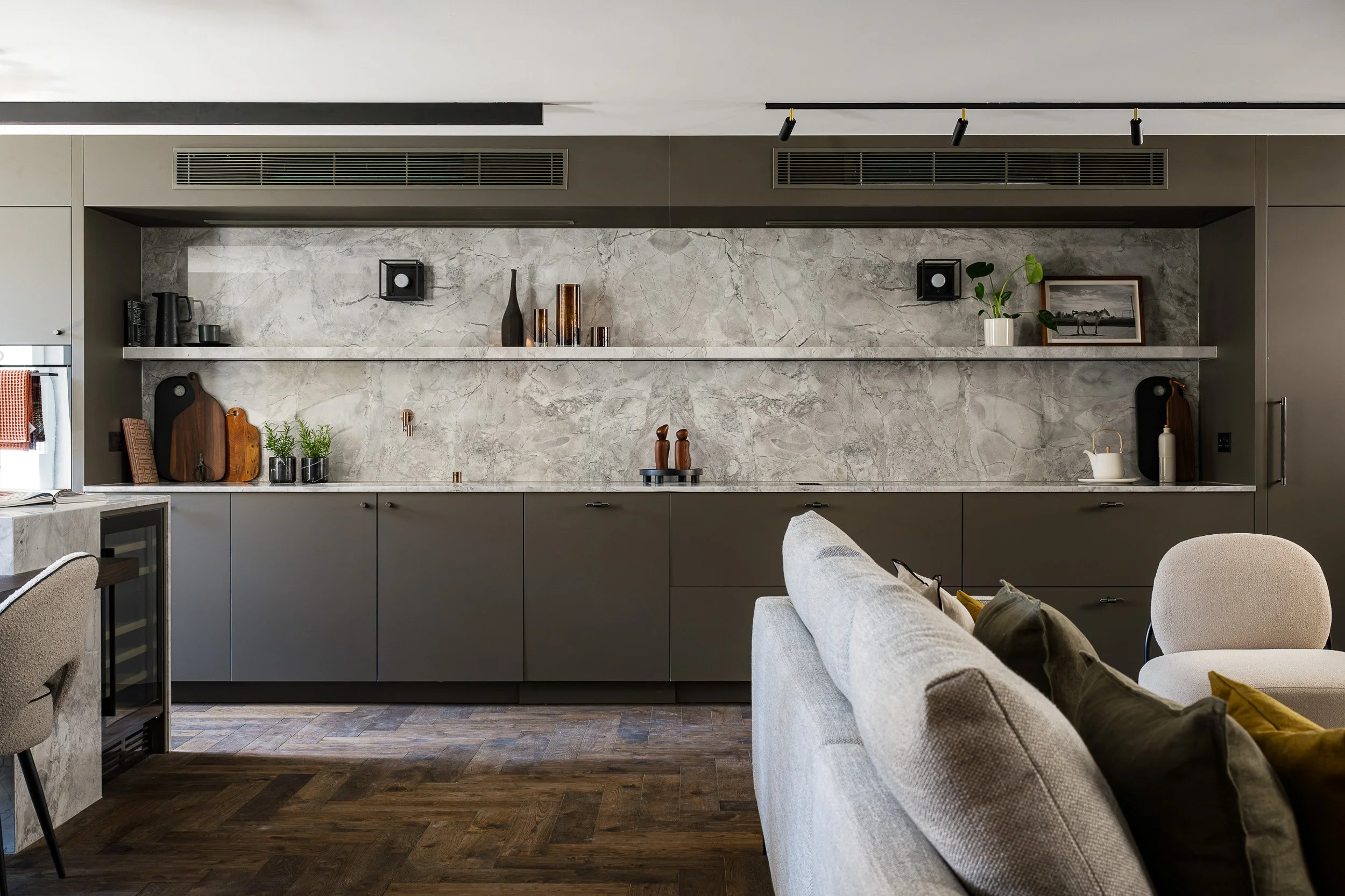 Open-plan living room and kitchen with dark cabinetry and a marble splashback.