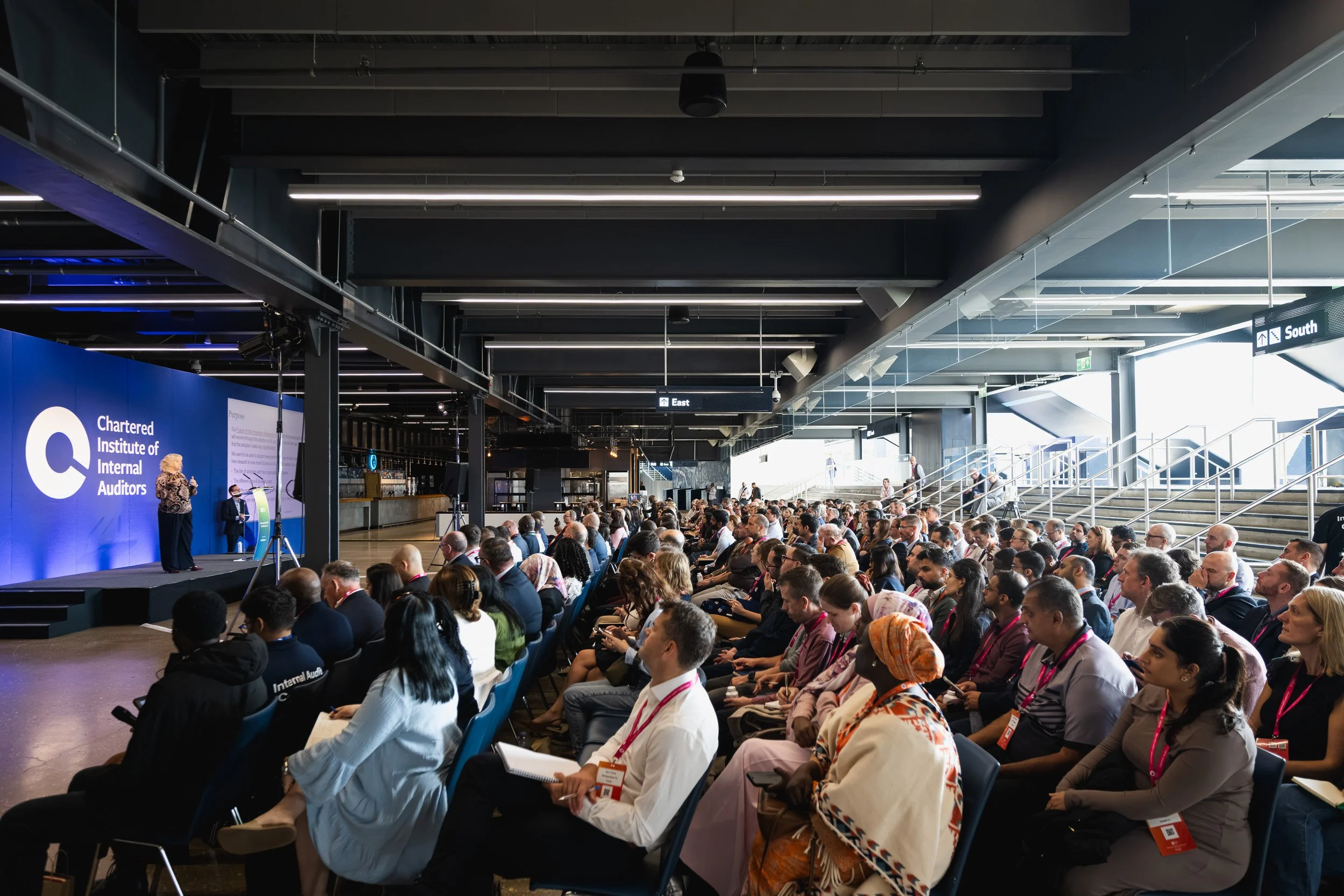 Delegates seated in the main conference space at Tottenham Hotspur Stadium.