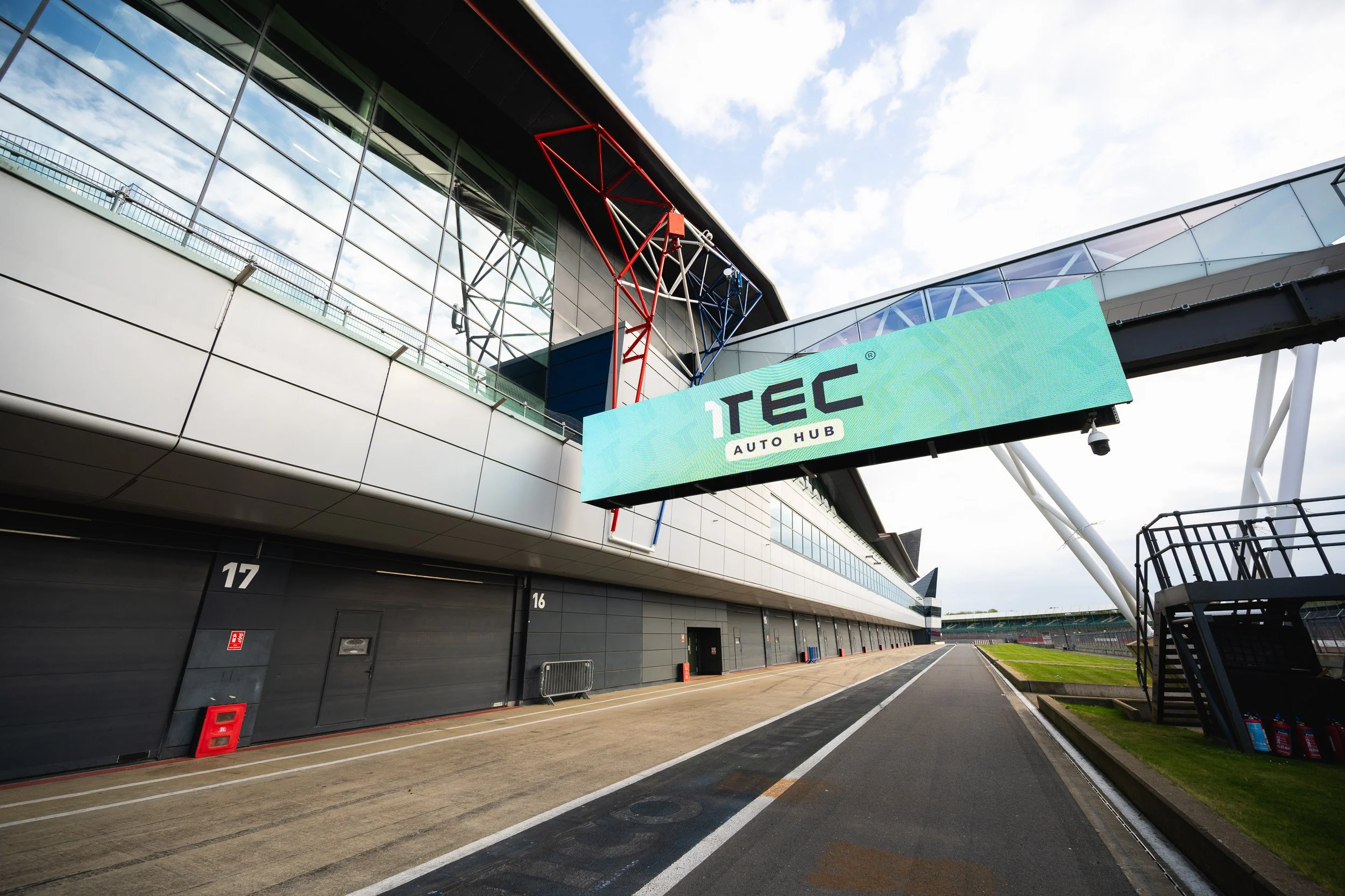 1TEC Auto Hub branding above the Silverstone pit lane, with garage buildings alongside.