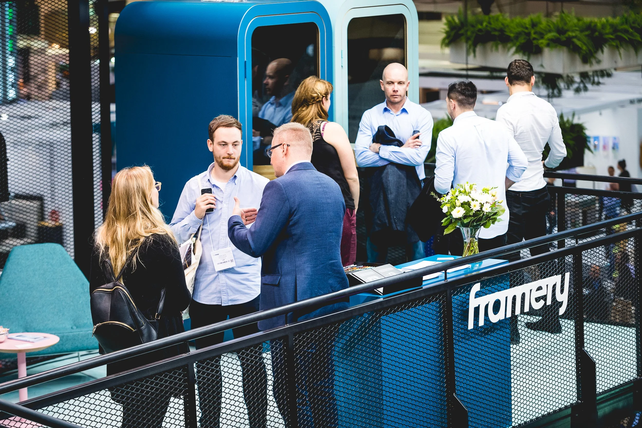 Visitors talking on the upper level of the Framery exhibition stand.