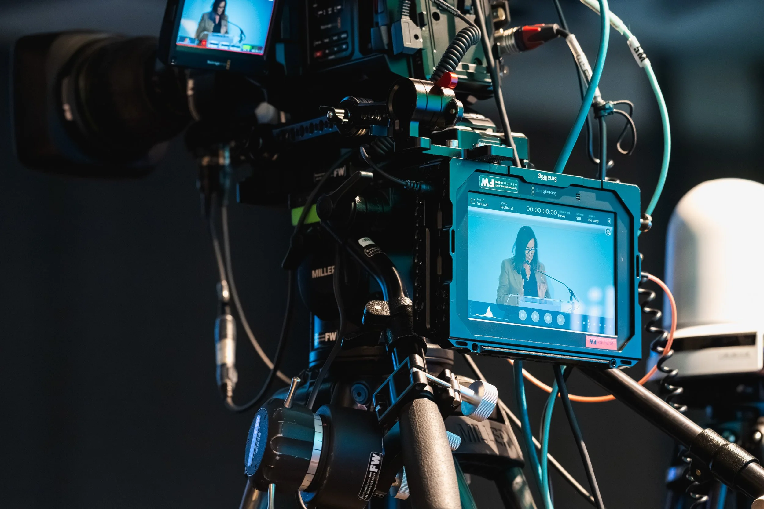 Professional video camera filming a speaker during the conference.