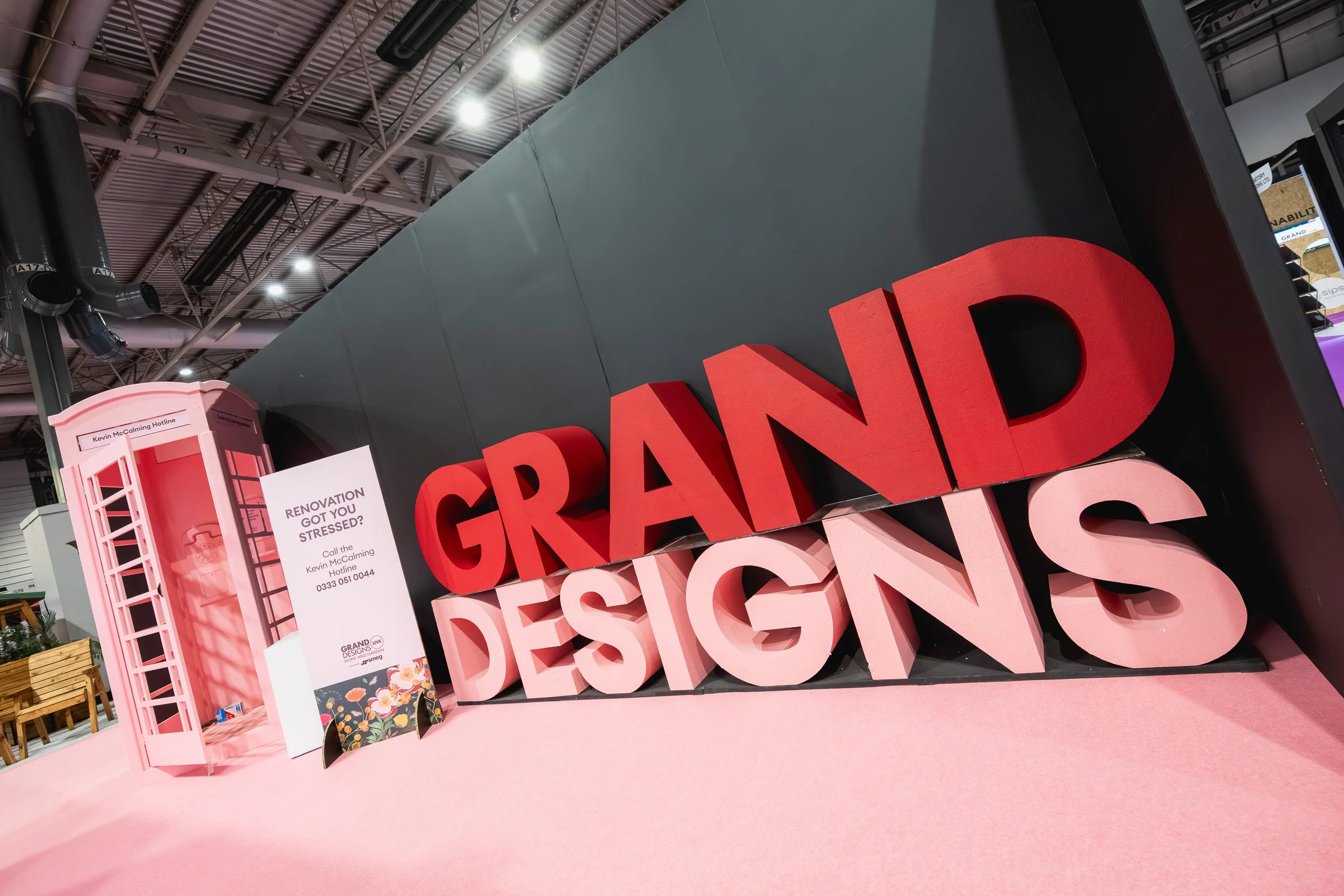 Large Grand Designs lettering beside a pink telephone-box display at the NEC.