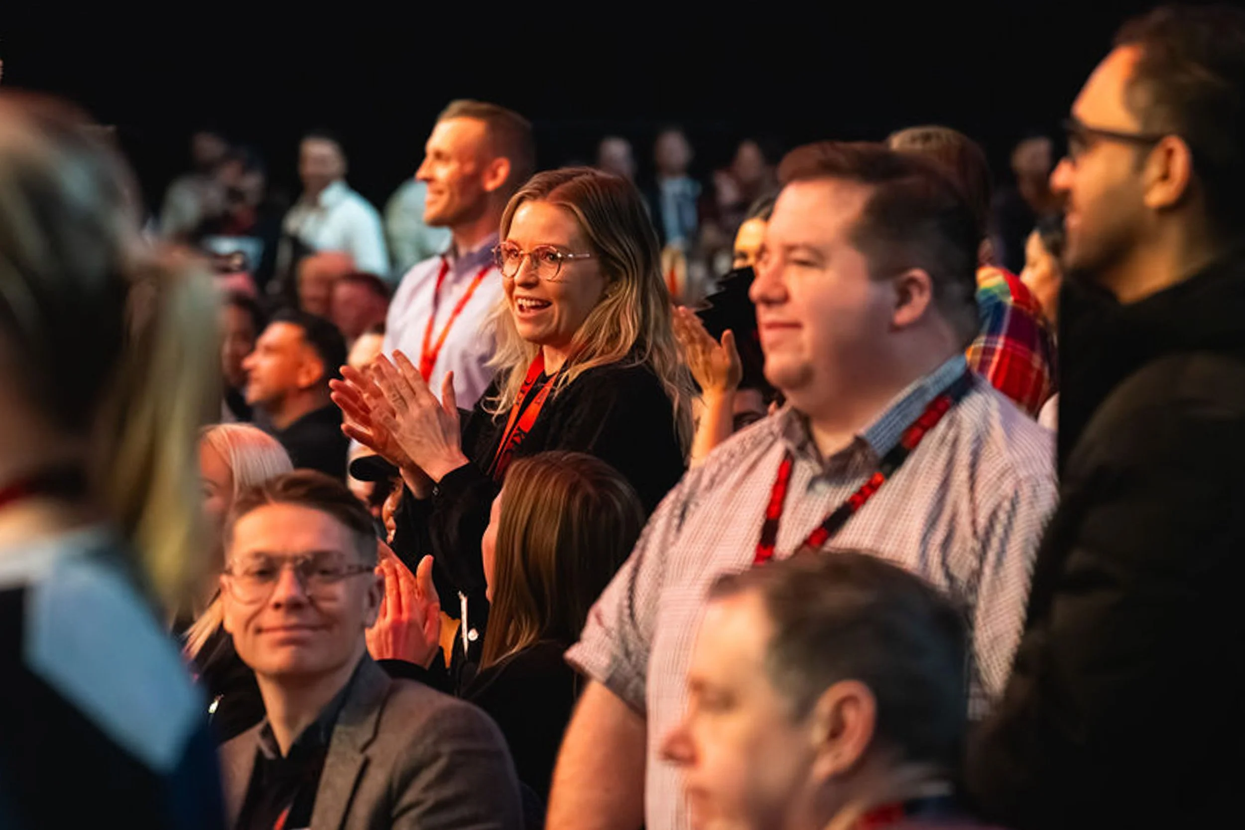A smiling delegate applauding among the audience at the KFC conference.