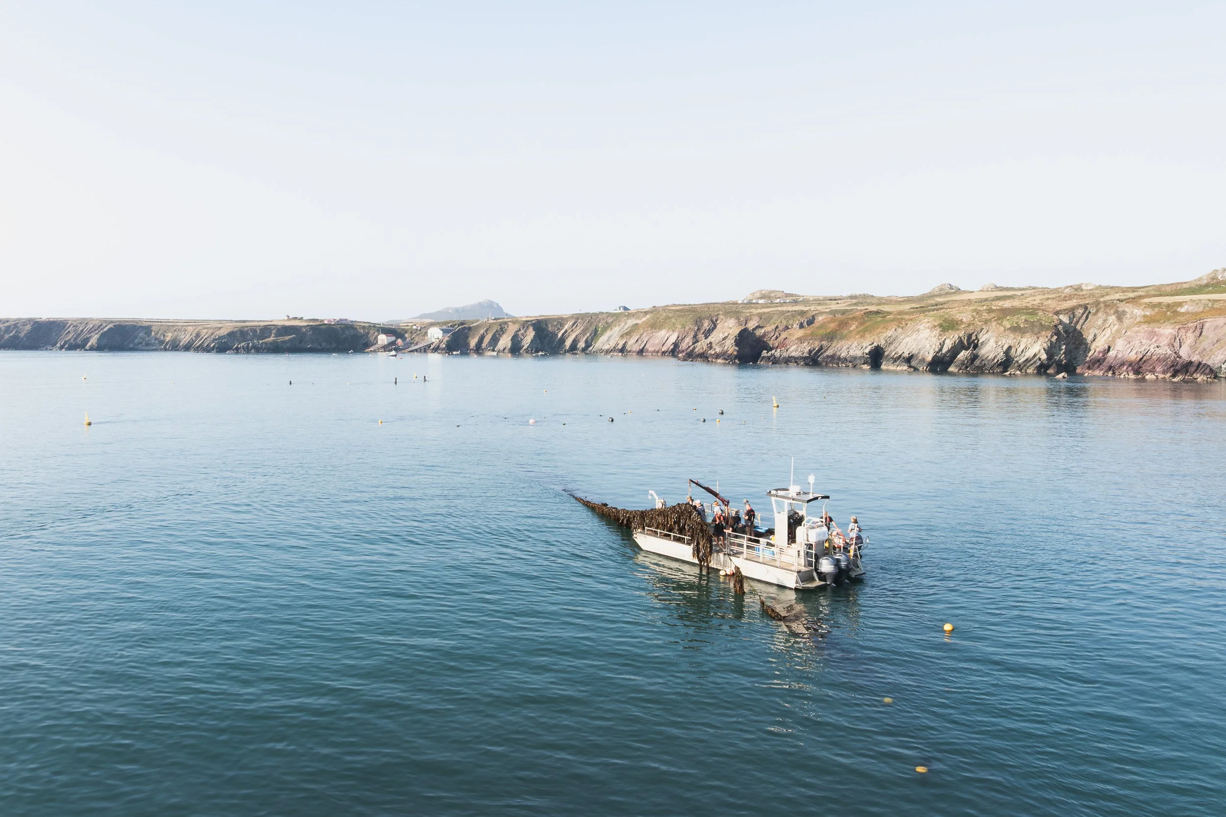 Boat on calm water beside the Welsh coastline.