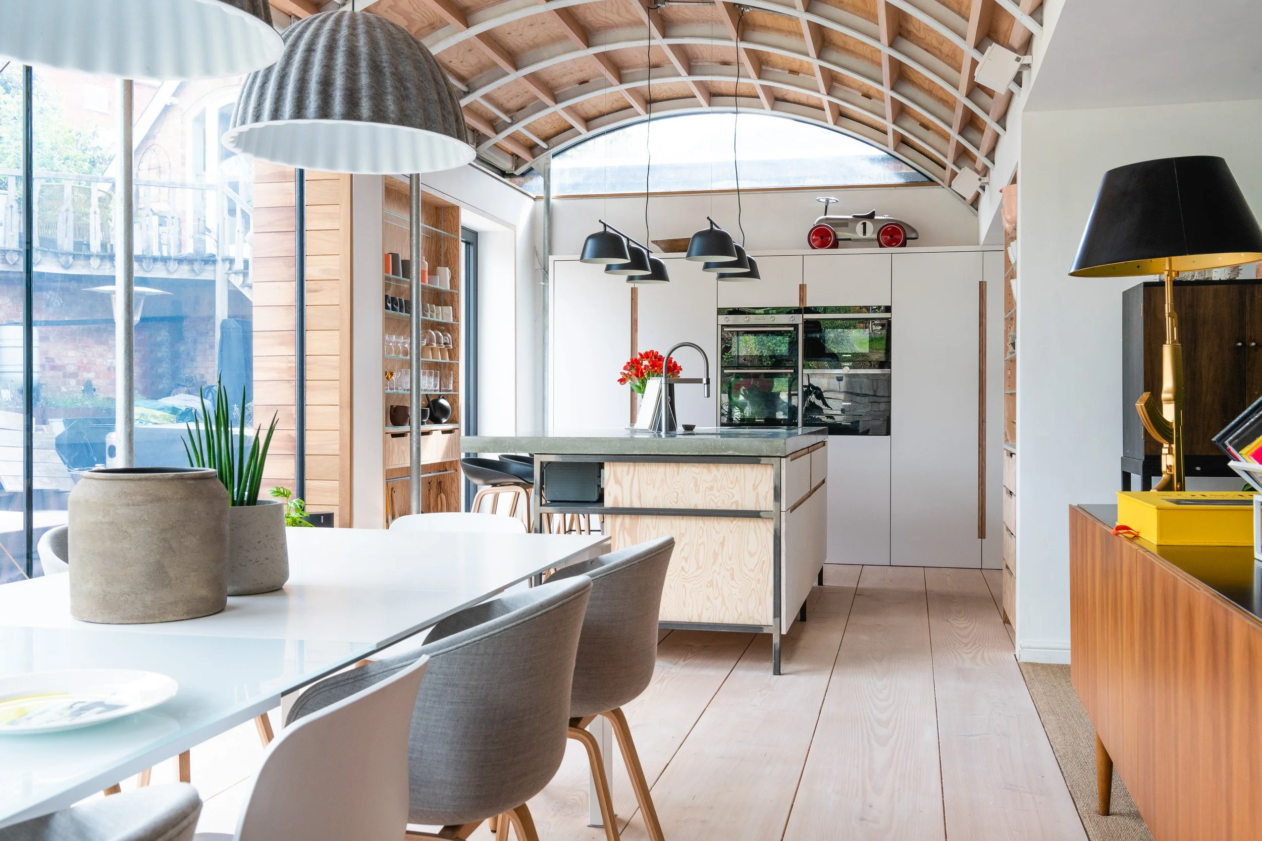Open-plan kitchen and dining room beneath a curved timber ceiling.
