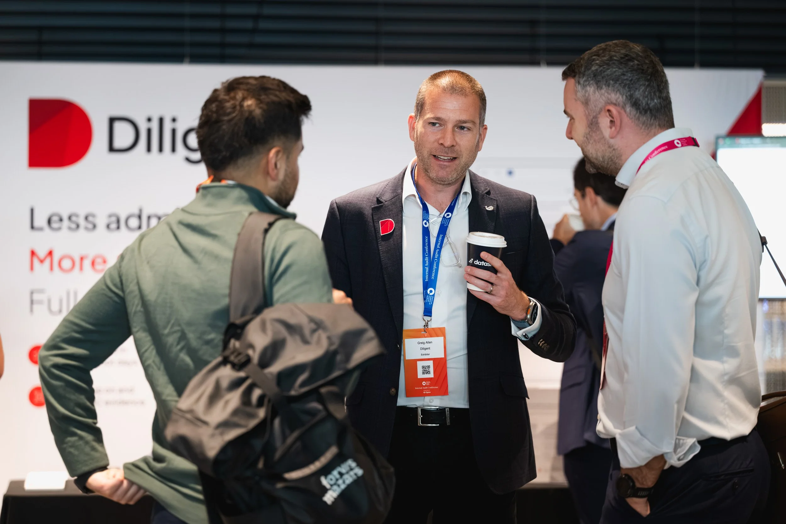 Three delegates talking beside an exhibition stand.