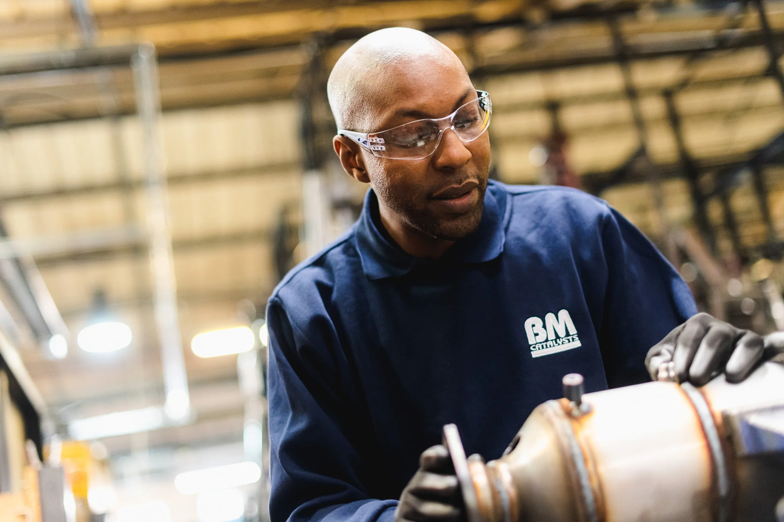 Engineer working on a mechanical component in an industrial workshop.