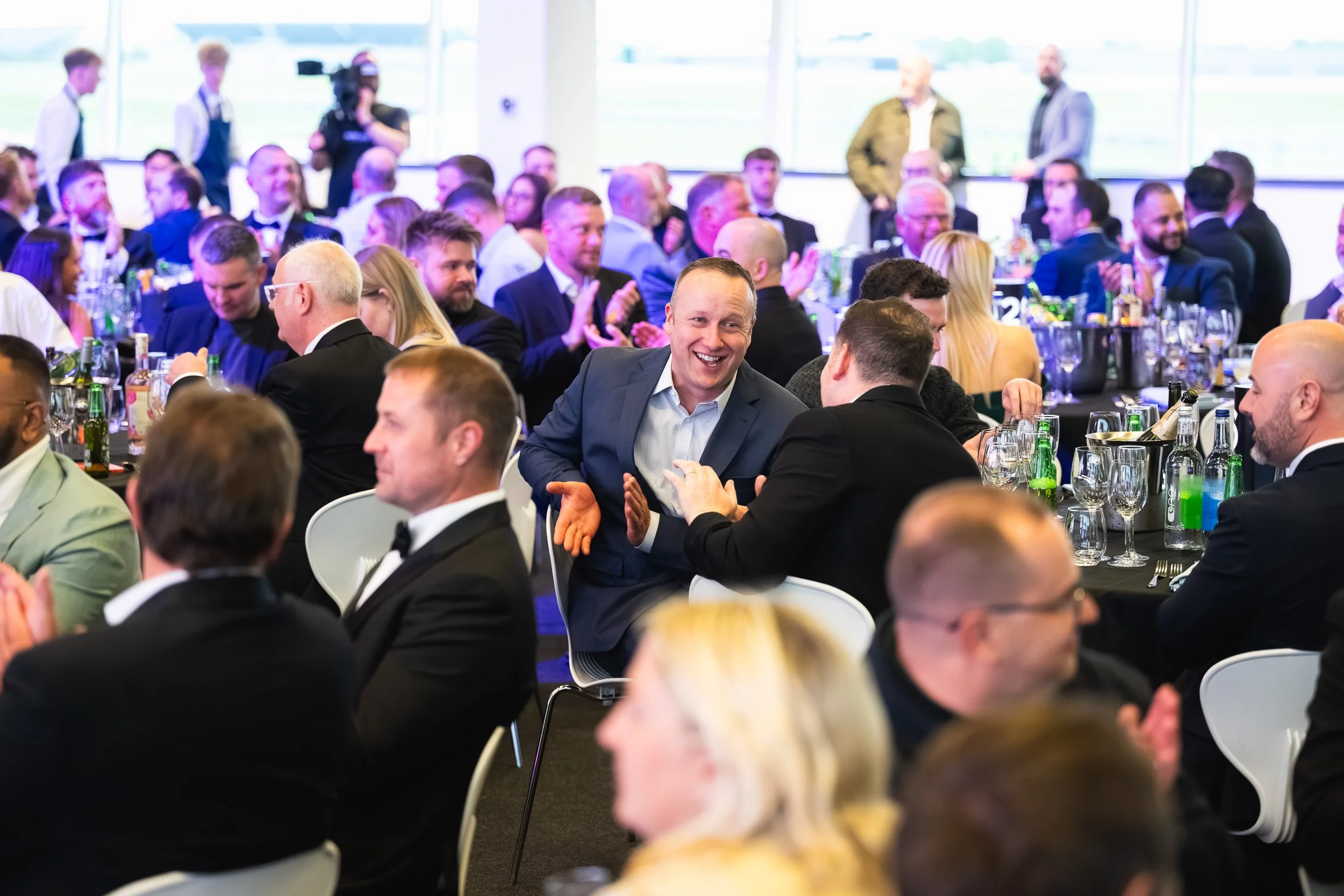 Guests smiling and applauding around dinner tables at the 1TEC evening event.