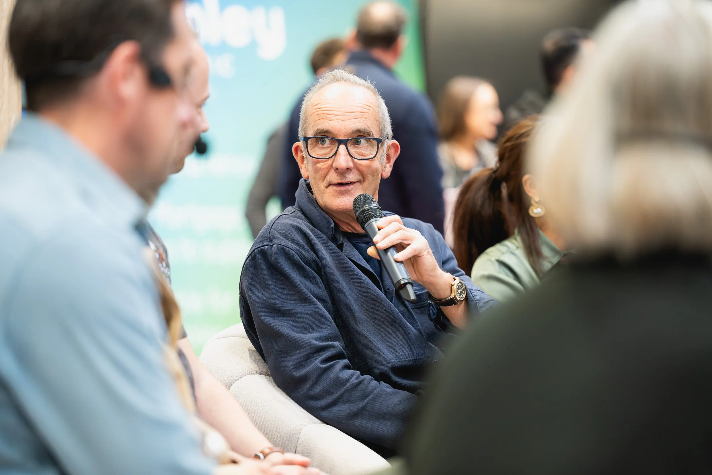Kevin McCloud holding a microphone during a discussion at Grand Designs Live.