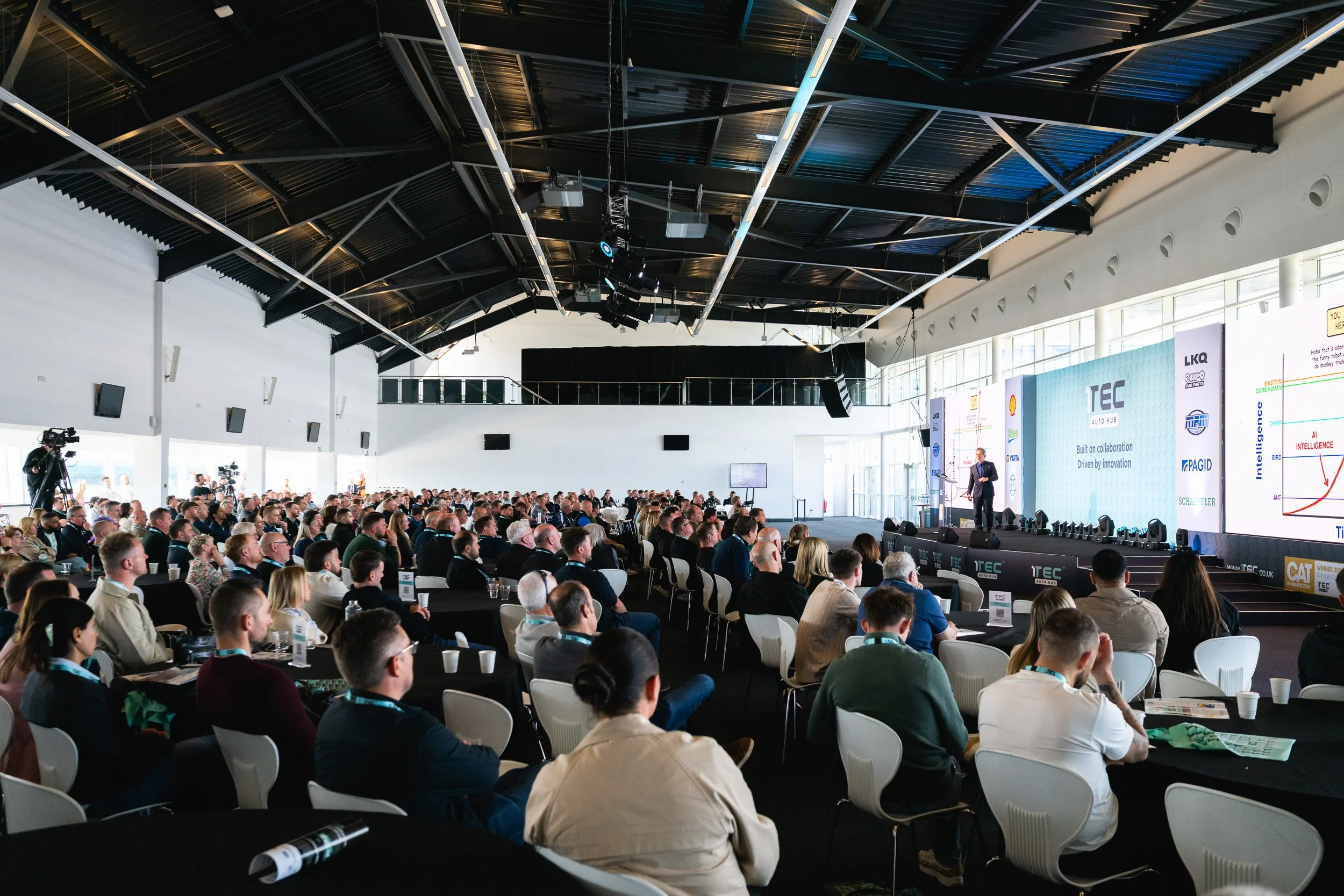 Delegates seated at tables facing the stage during the 1TEC conference at Silverstone.