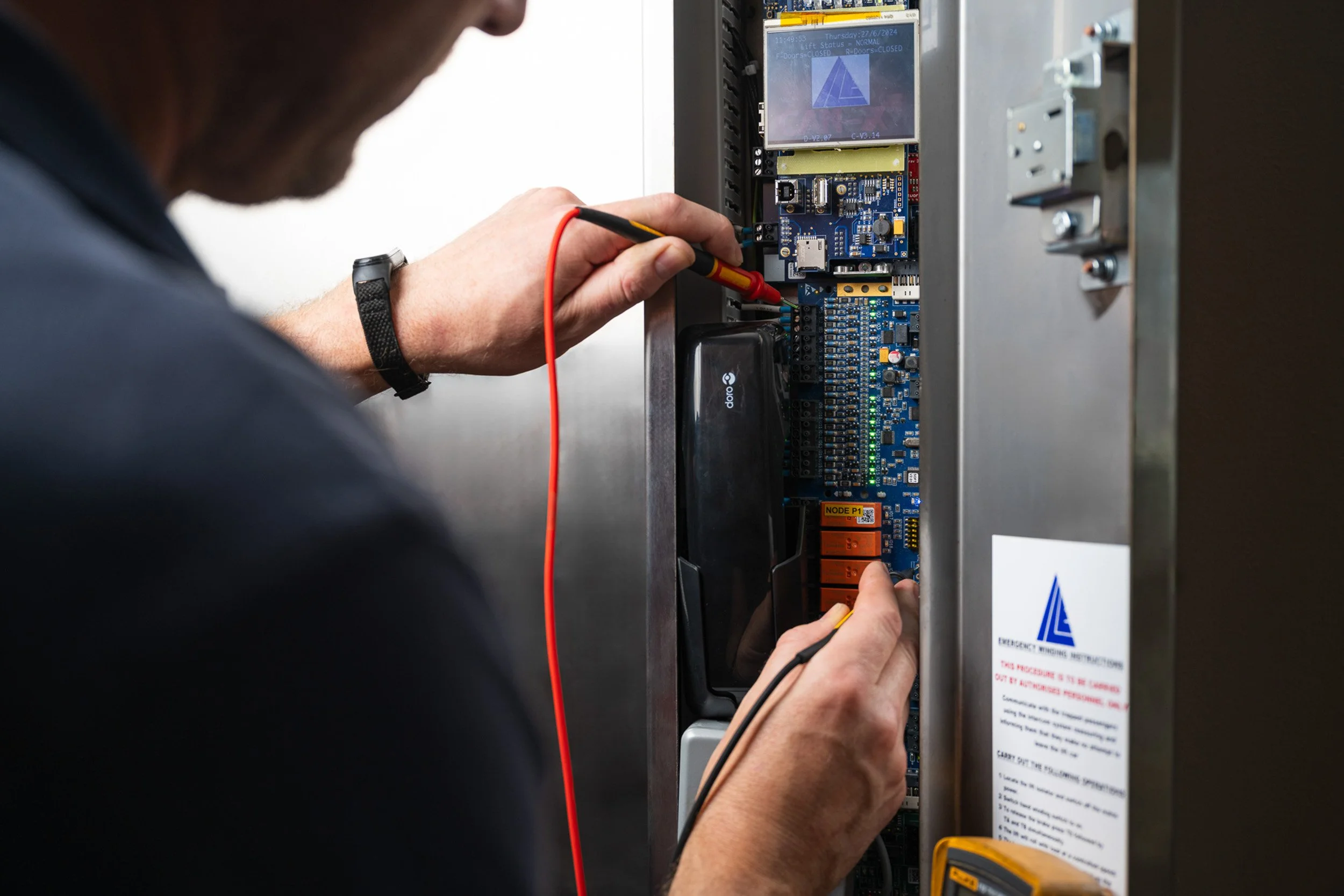 Technician testing an electrical control panel with probes.