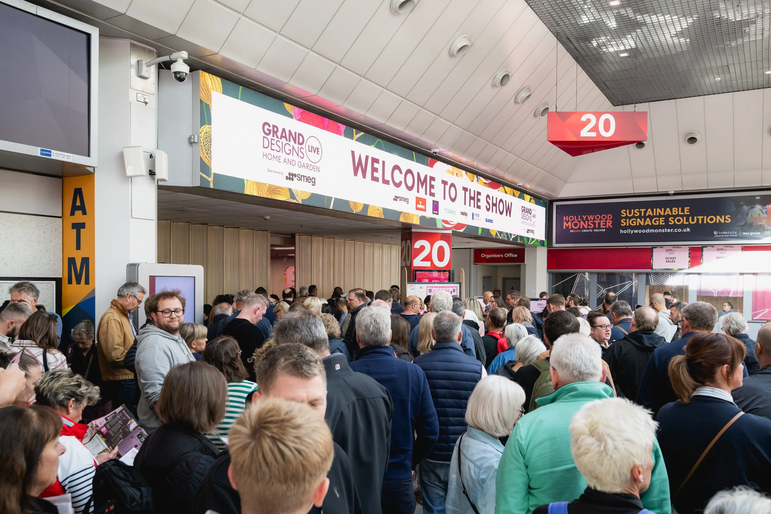 Visitors gathering beneath the Grand Designs Live welcome sign at the NEC Birmingham.