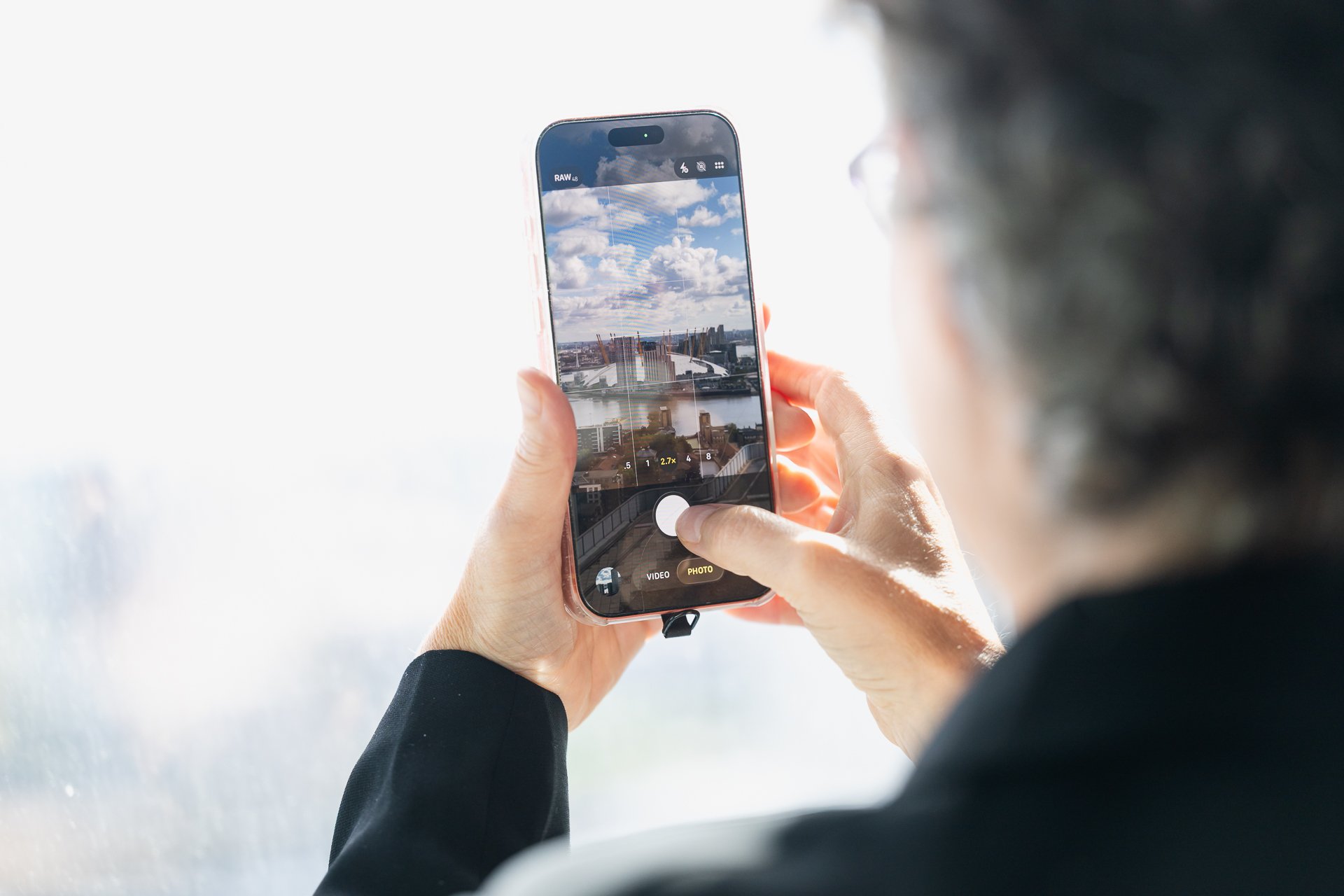 A delegate holding up a phone to photograph the view through a large window.