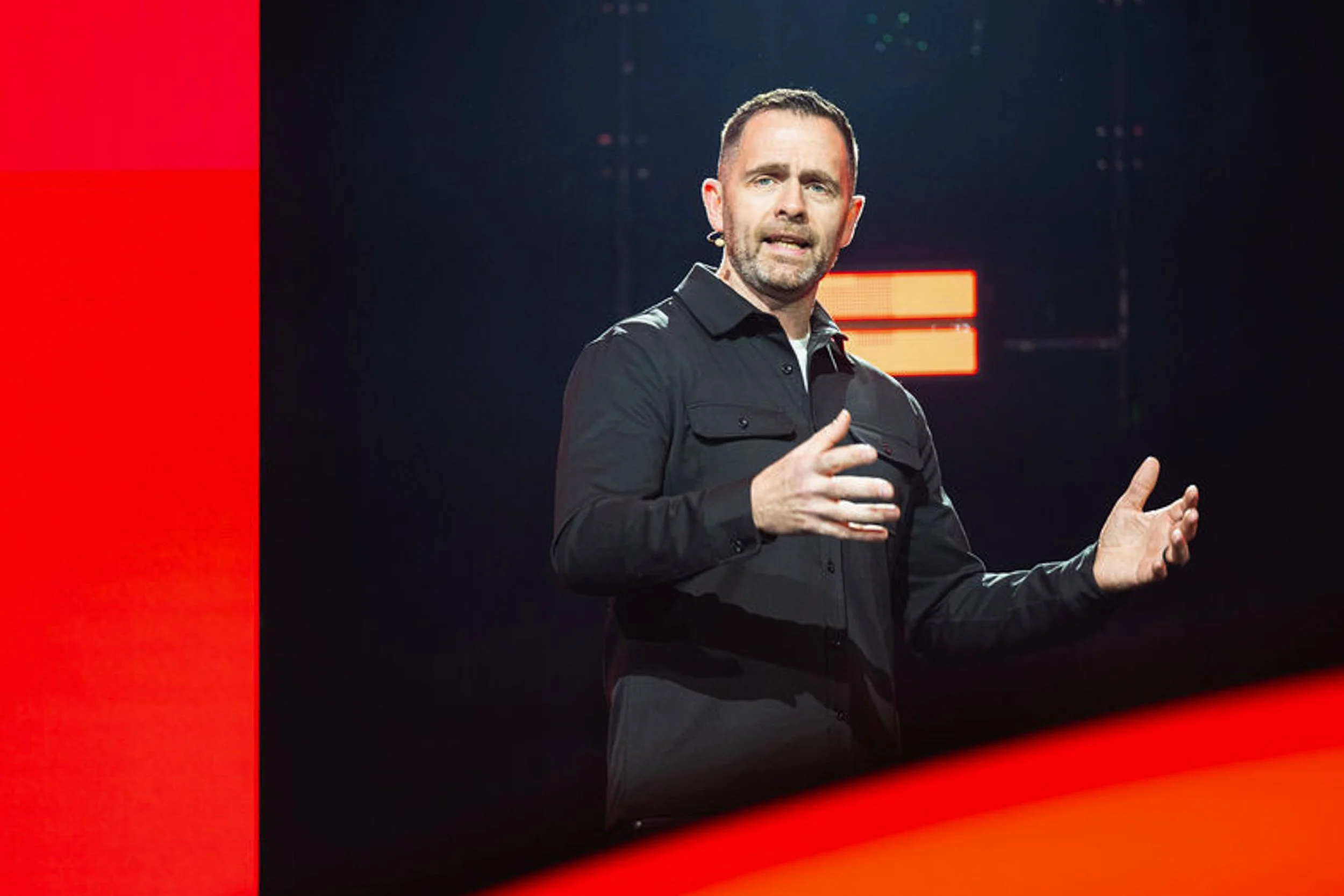 Speaker gesturing during a presentation on the KFC conference stage.