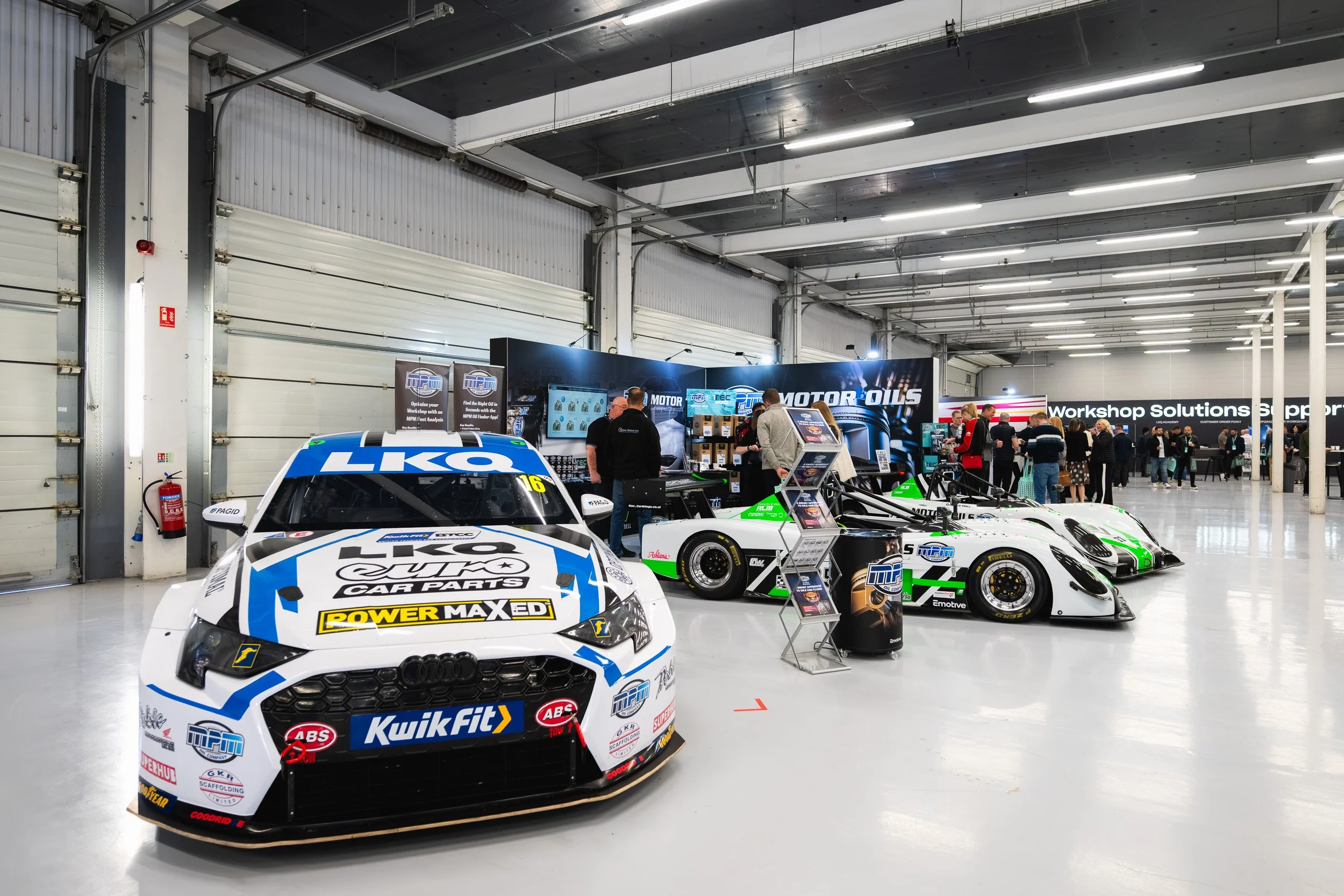 Racing cars displayed in front of exhibition stands at the 1TEC event at Silverstone.