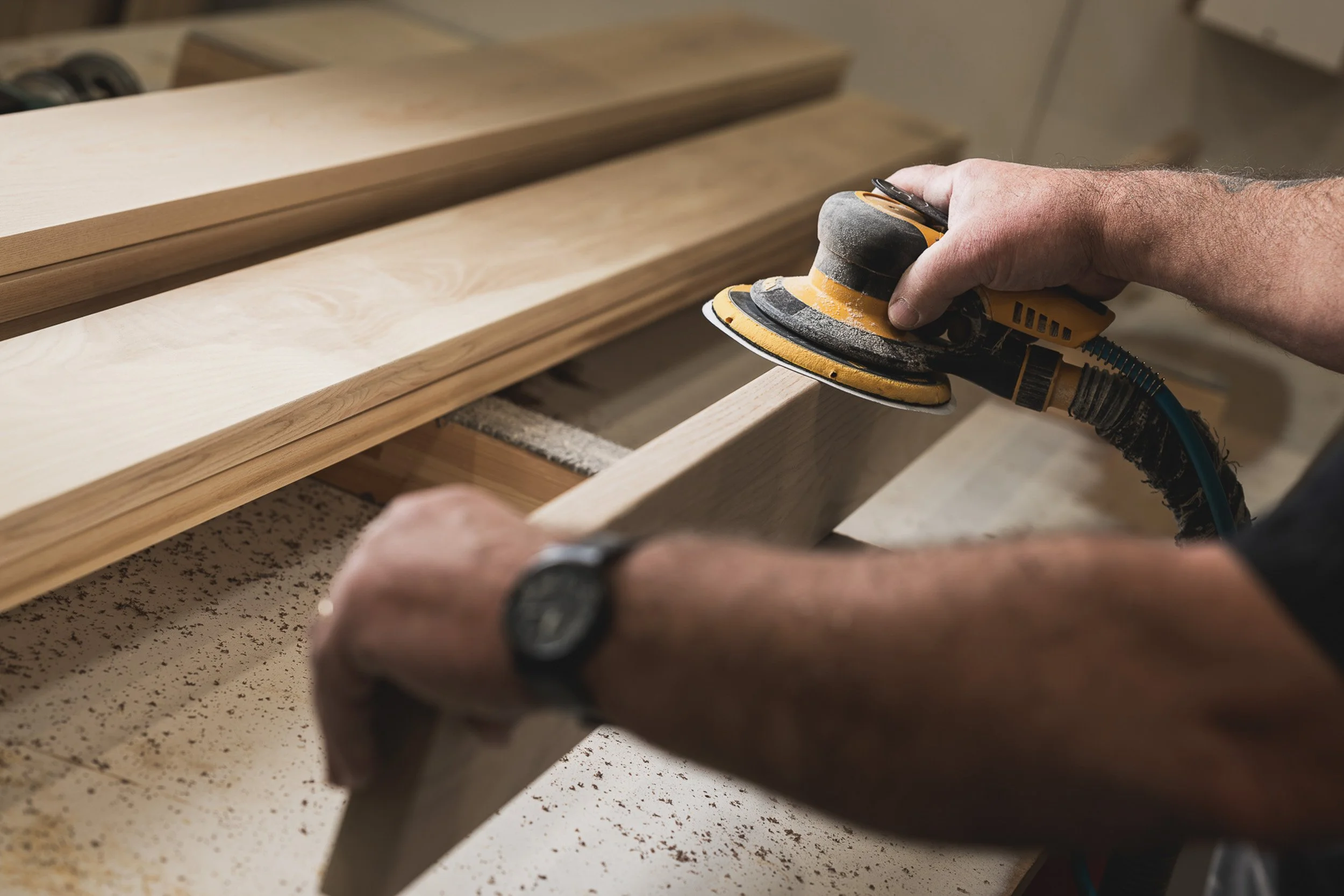 Worker sanding a timber component in a workshop.