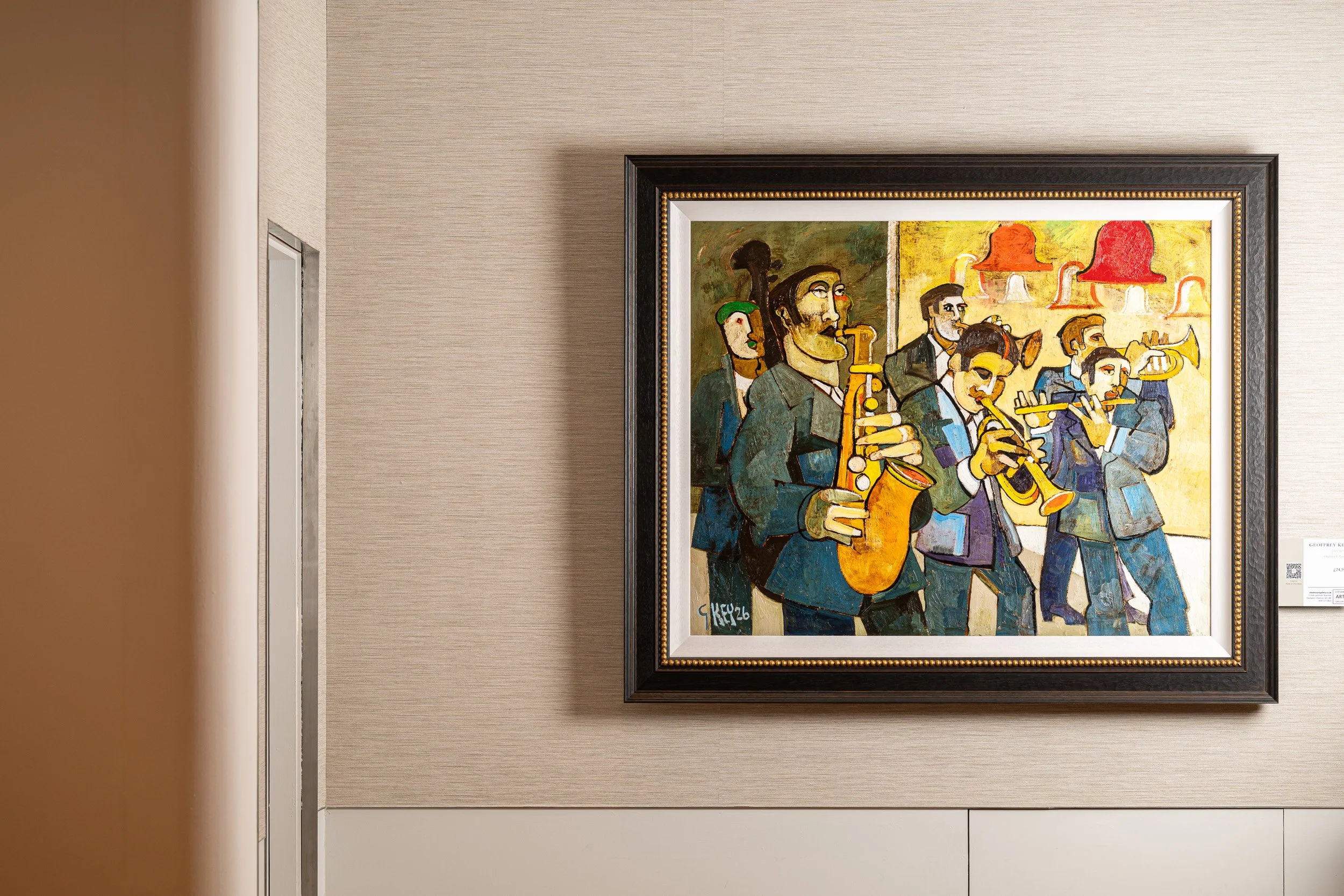 Colourful painting of musicians in a dark frame on a pale wall.