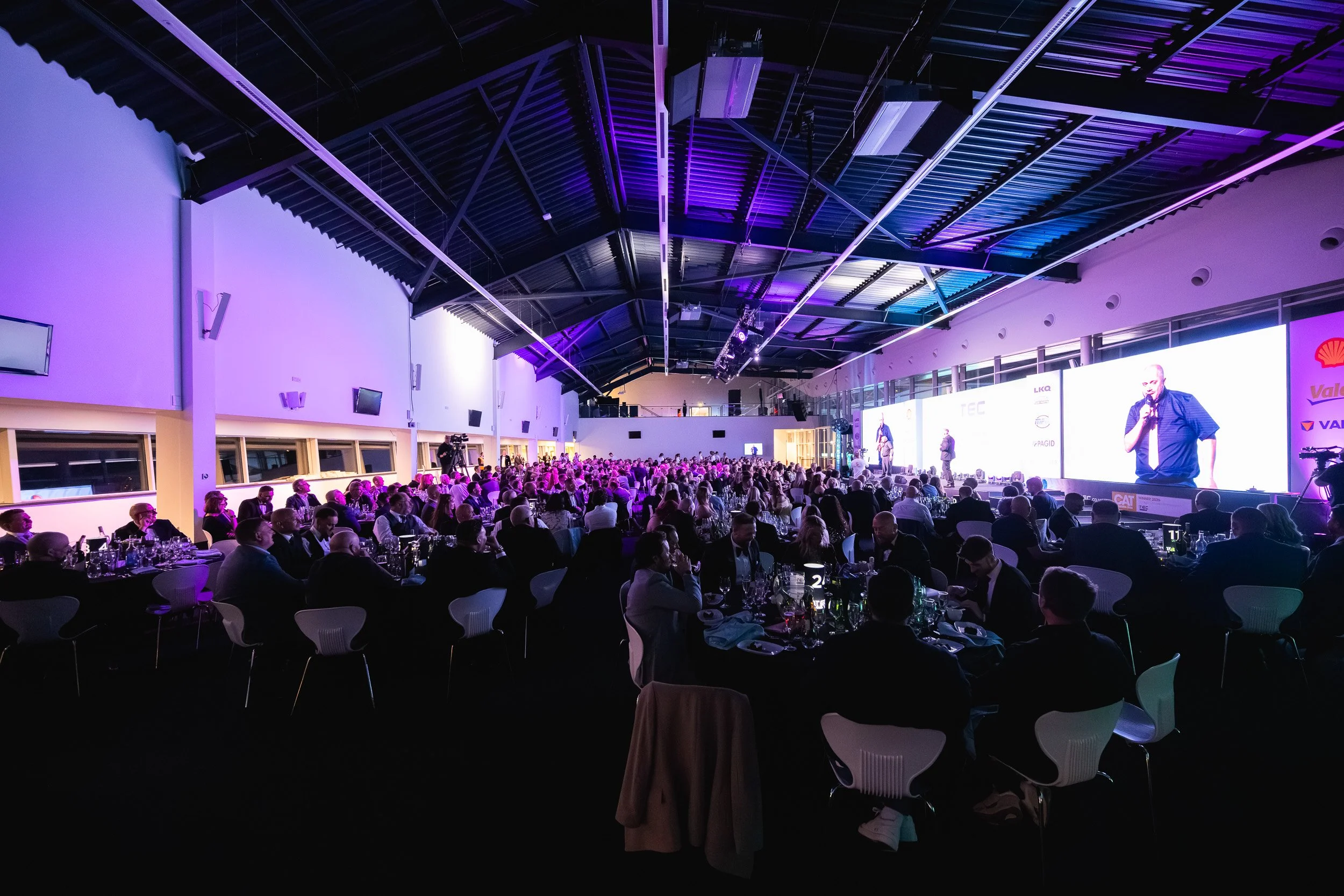 Guests seated at dinner tables beneath purple and blue lighting at the 1TEC awards dinner.
