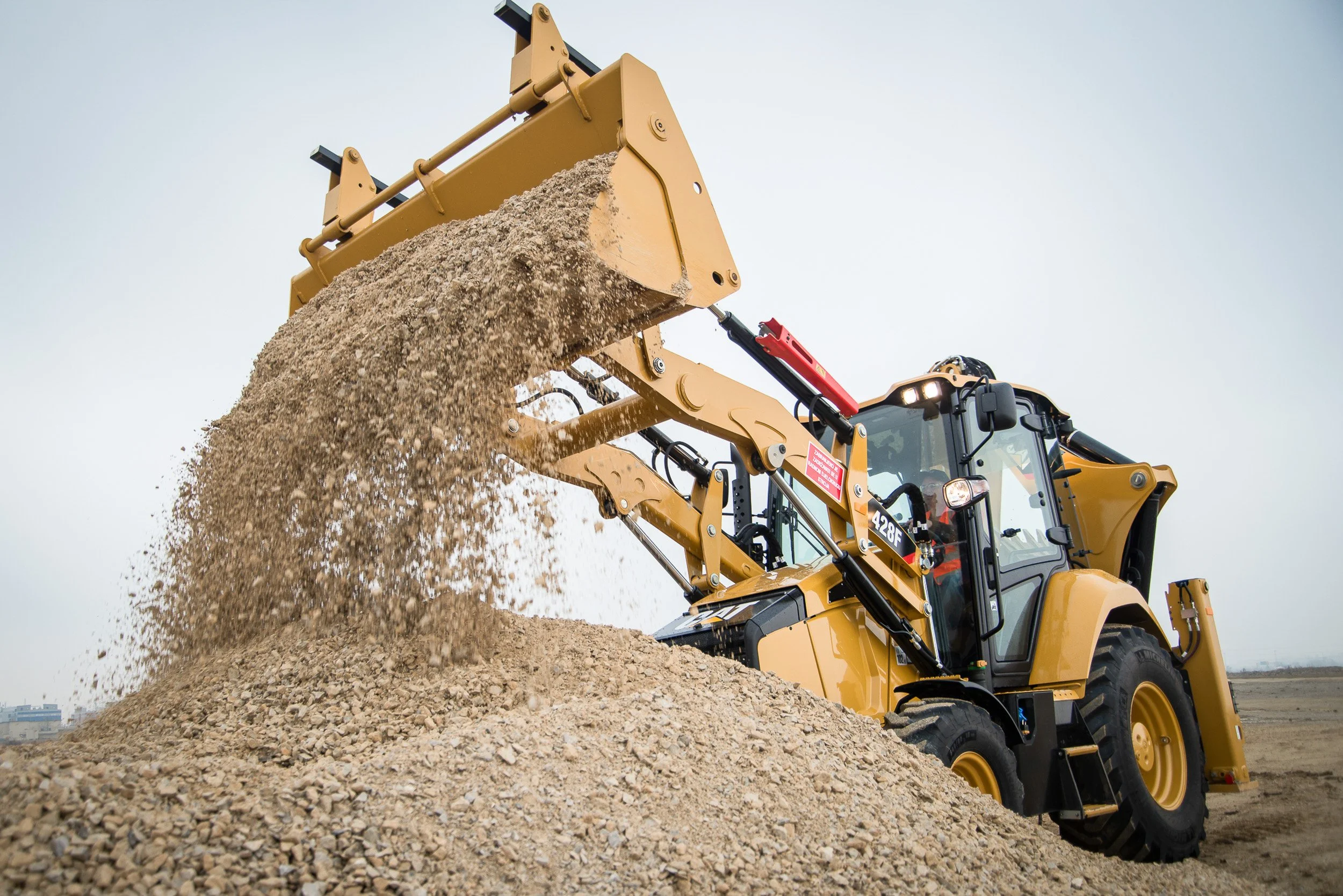 Loader tipping aggregate onto a pile at an outdoor worksite.