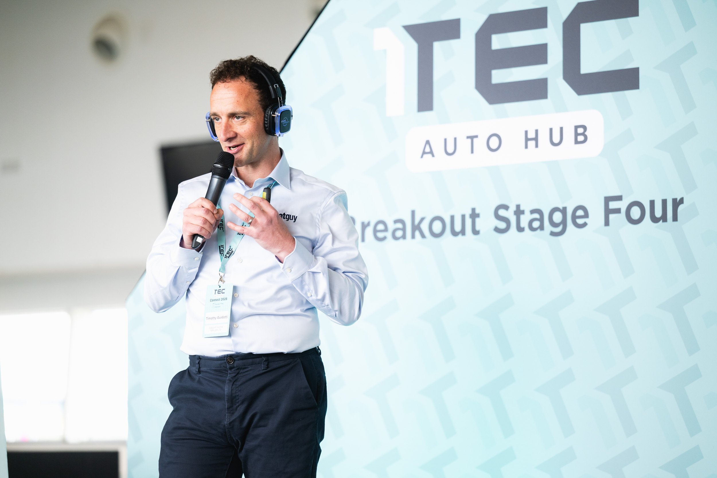 Speaker wearing headphones and holding a microphone on 1TEC Breakout Stage Four.