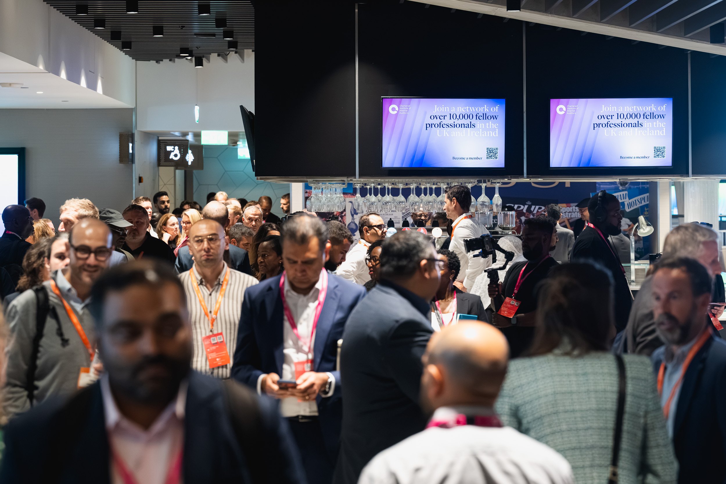 Delegates walking through a busy exhibition area at the Internal Audit Conference.