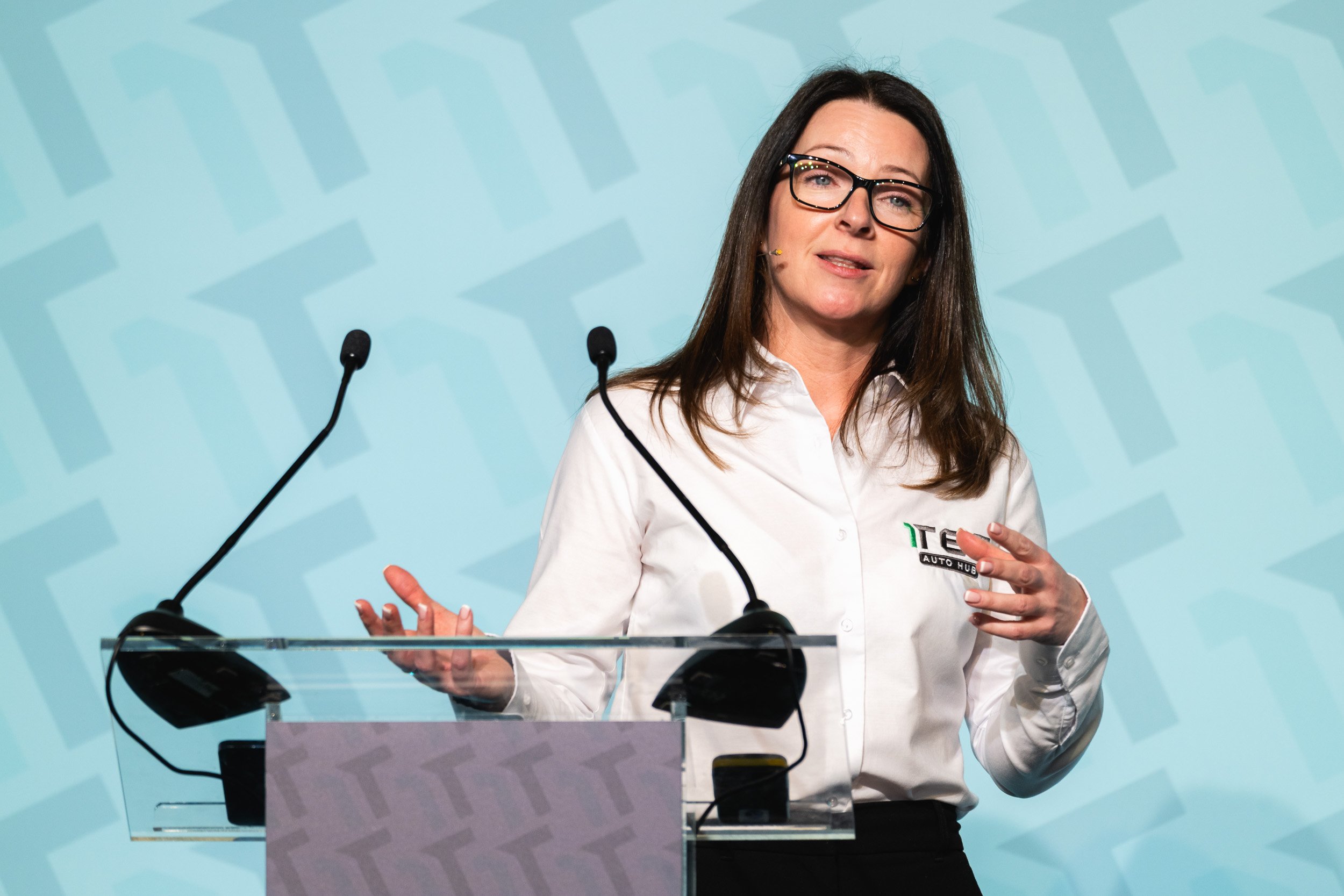 Speaker presenting from a clear lectern at the 1TEC conference.