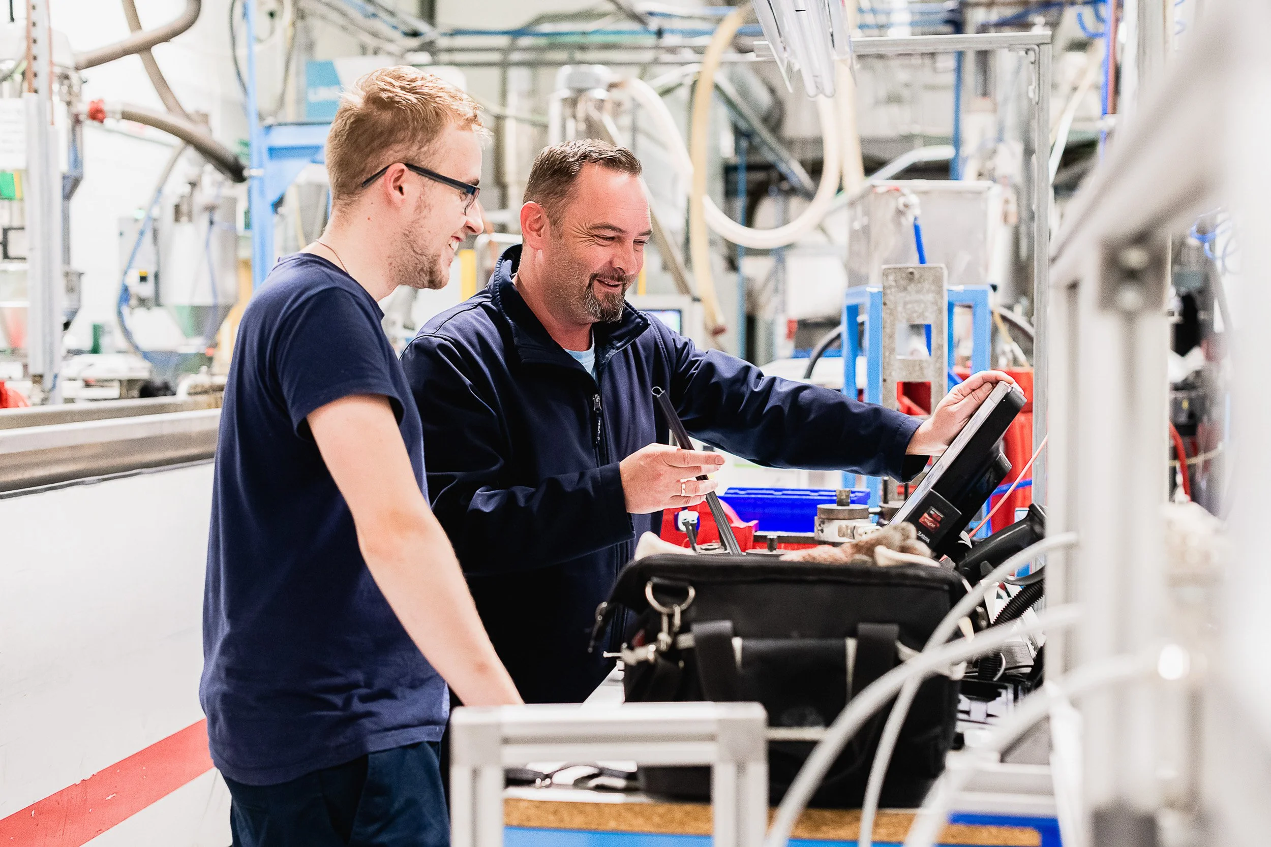 Two workers checking equipment on a factory production line.