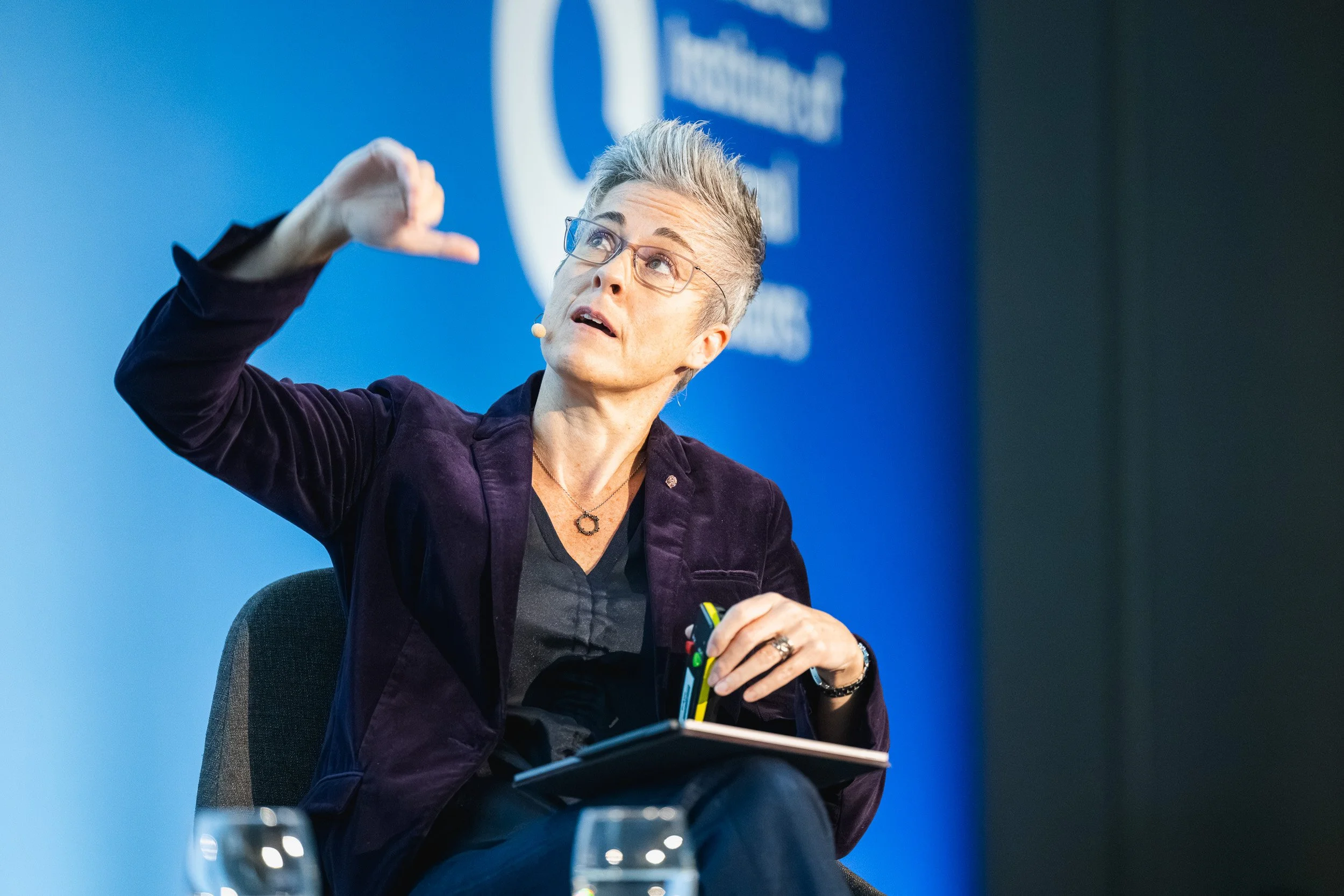 Speaker gesturing during a presentation against Chartered IIA branding.