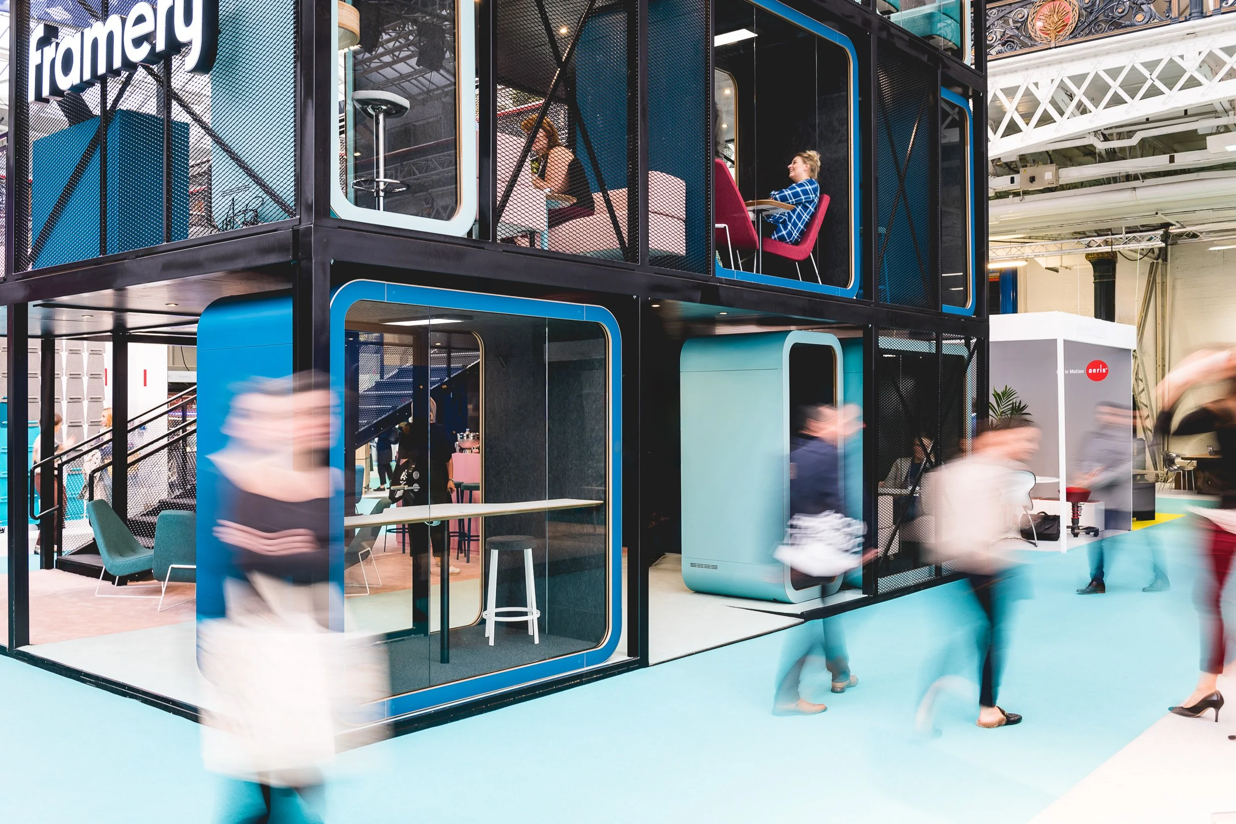 Visitors walking past a two-storey Framery exhibition stand at Olympia.