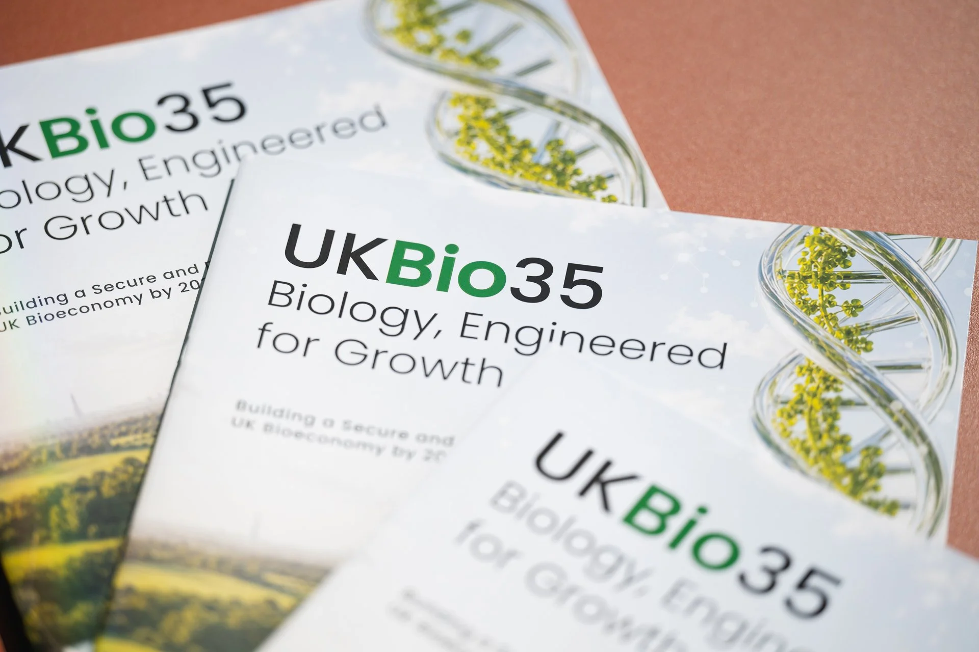Copies of a publication titled “UKBio35: Biology, Engineered for Growth” arranged on a table.