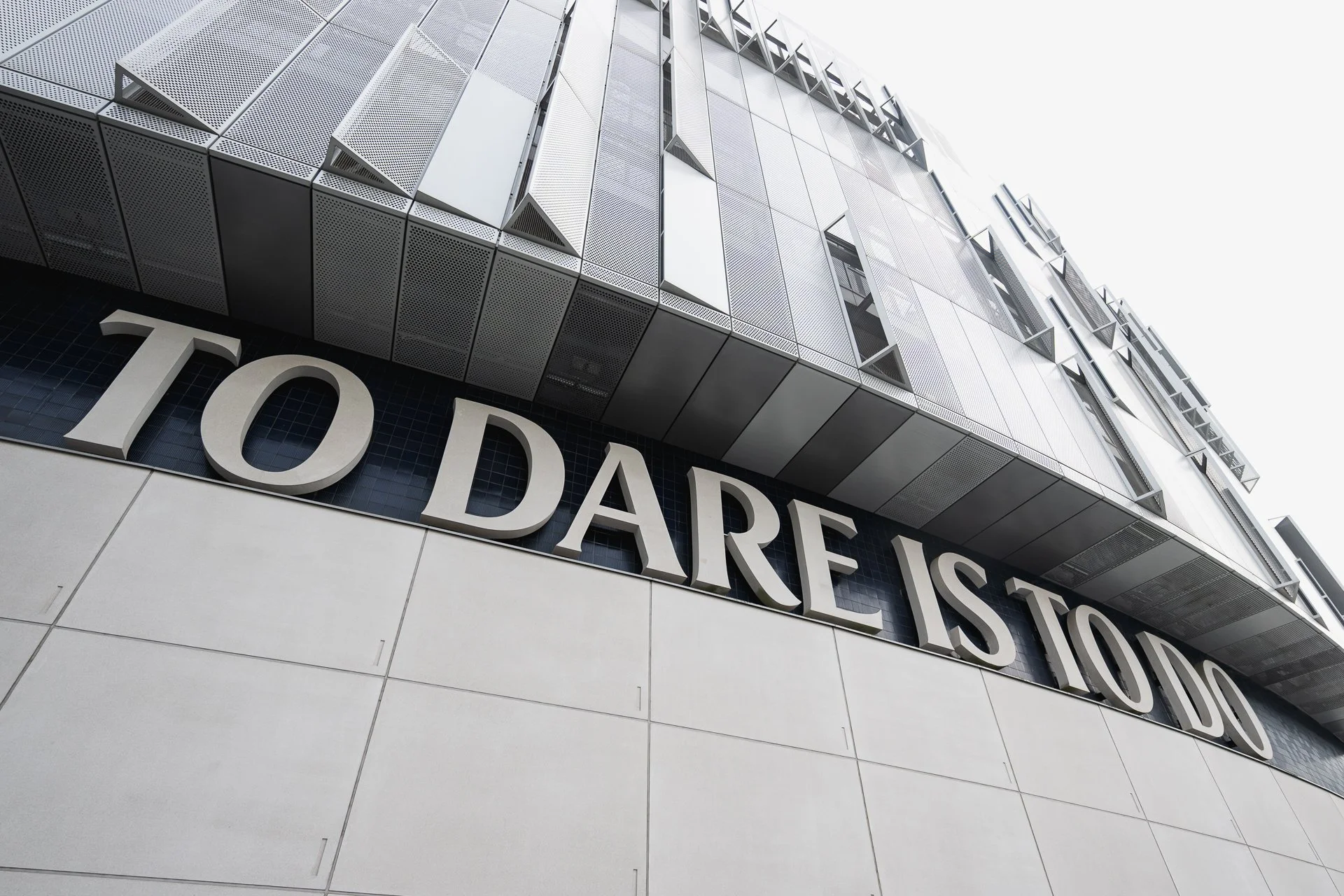Exterior detail of Tottenham Hotspur Stadium with To Dare Is To Do lettering.
