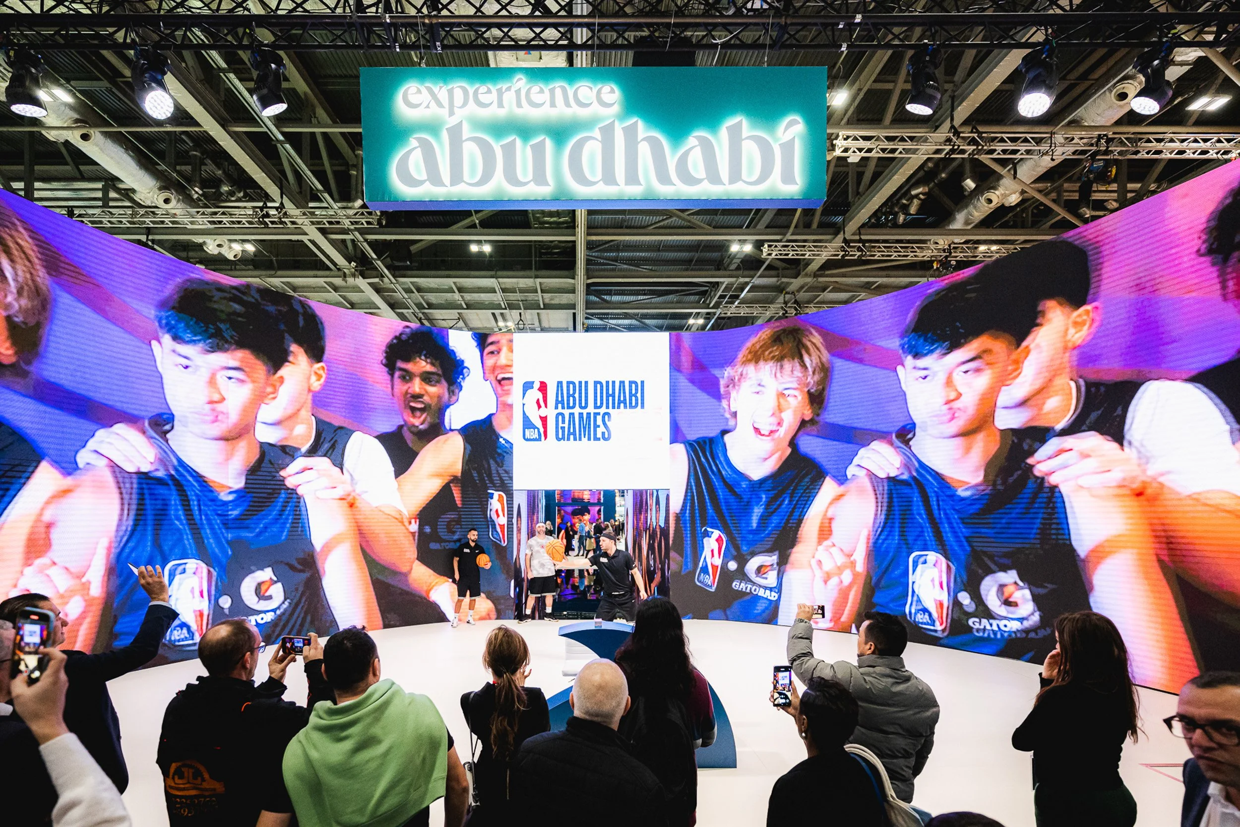 Visitors watching a large illuminated display on the Experience Abu Dhabi exhibition stand.