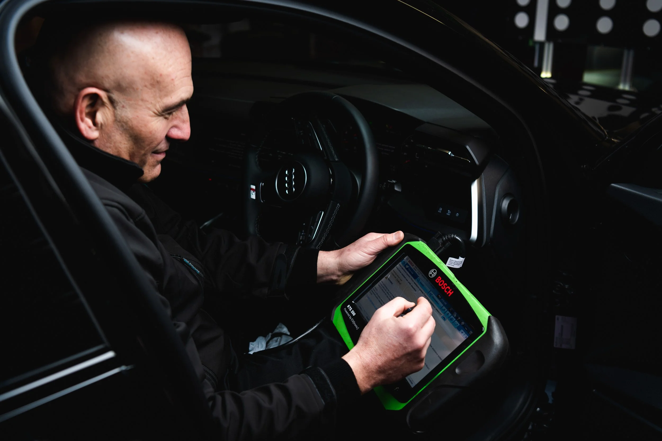 Technician using a diagnostic tablet inside a car.