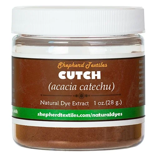 A plastic jar full of brown powder labeled "Cutch".