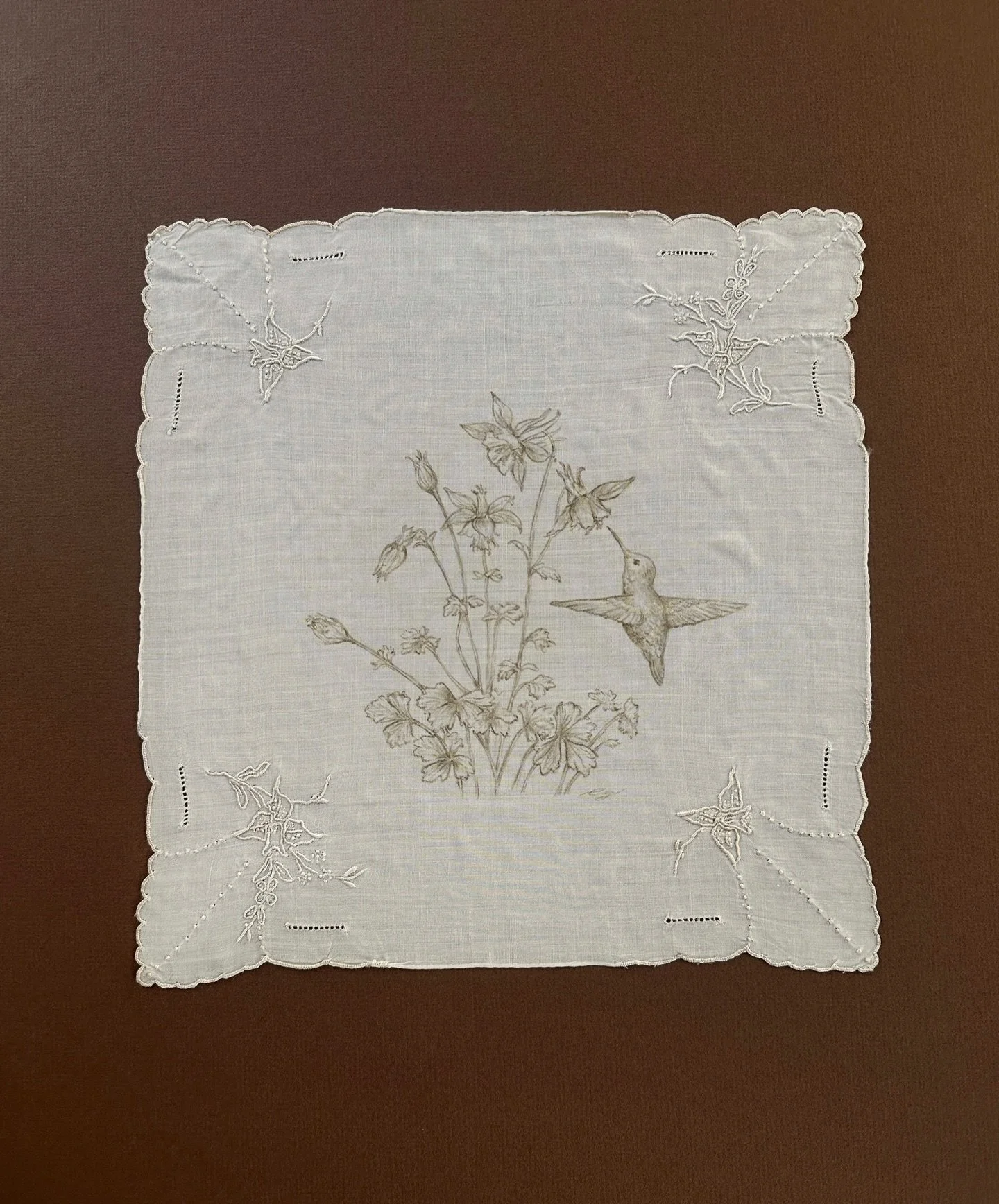 This vintage linen already held delicate, bell-shaped florals in each corner, softly reminiscent of the aquilegia flower, a favorite of hummingbirds. Drawing my own aquilegia and hummingbird at the center felt like a natural continuation of that lang