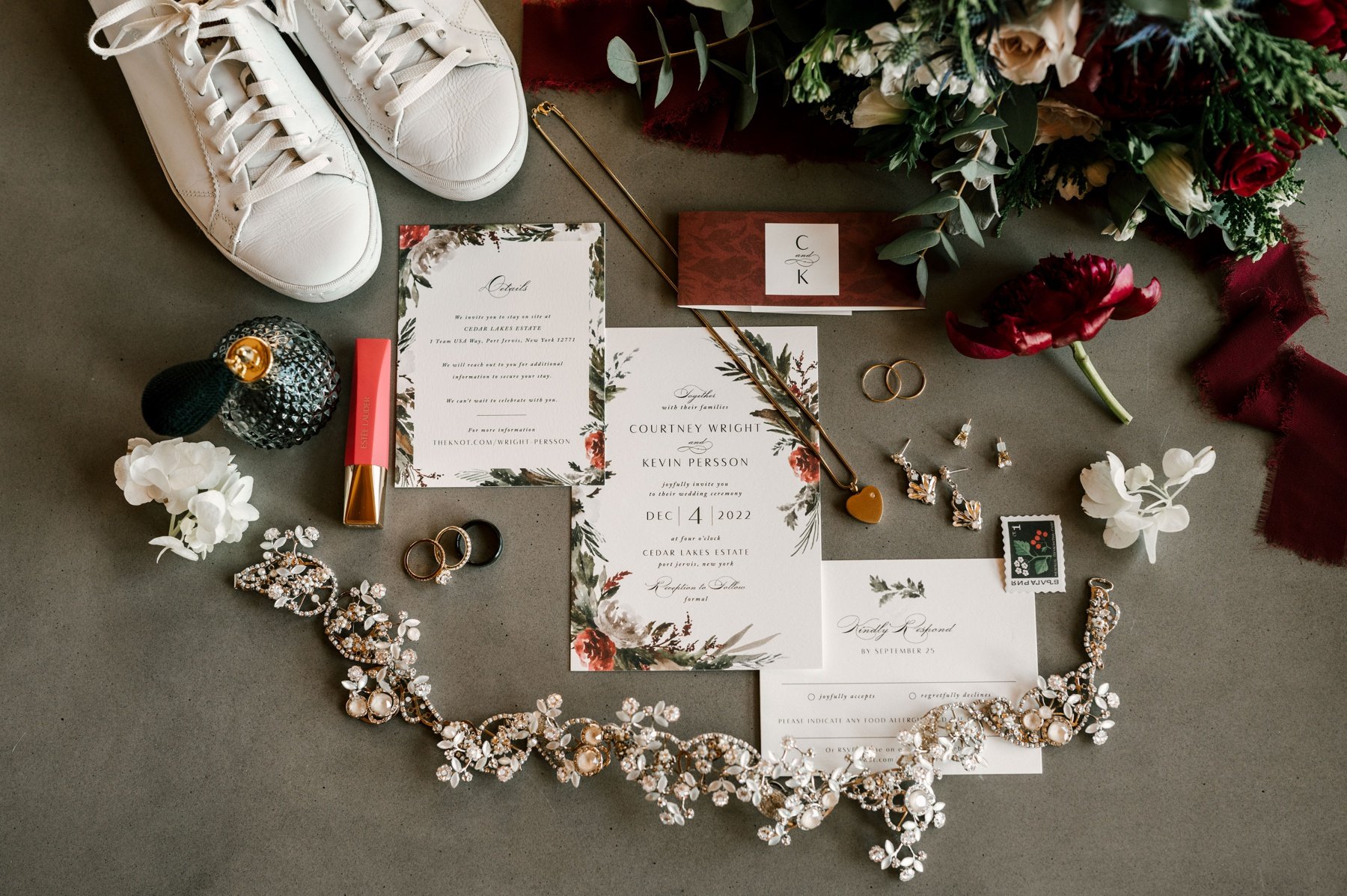 Flat lay of a winter wedding invitation with flowers and burgundy ribbon