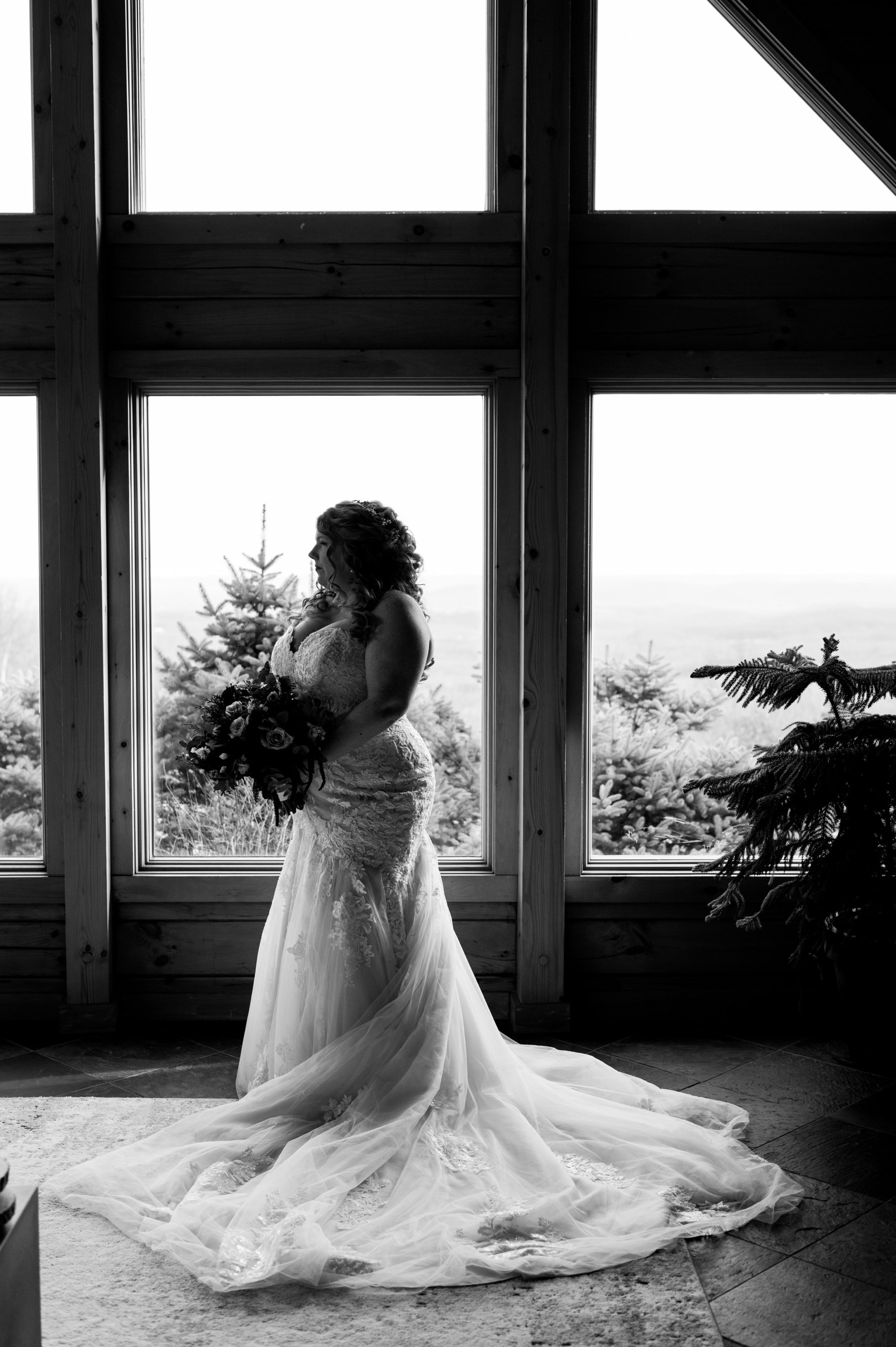 Black and white portrait of a bride standing in front of a window