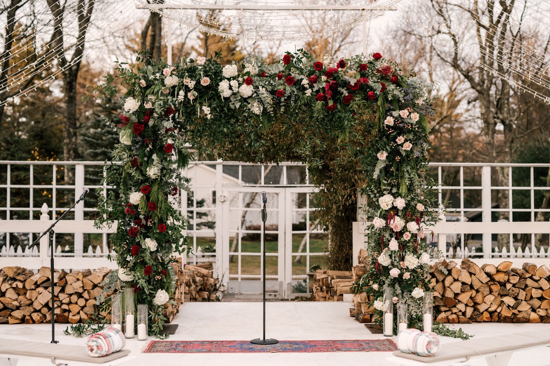 Floral arch with burgundy and blush roses, white hydrangeas, and candles by Metropolitan Plant &amp; Flower Exchange