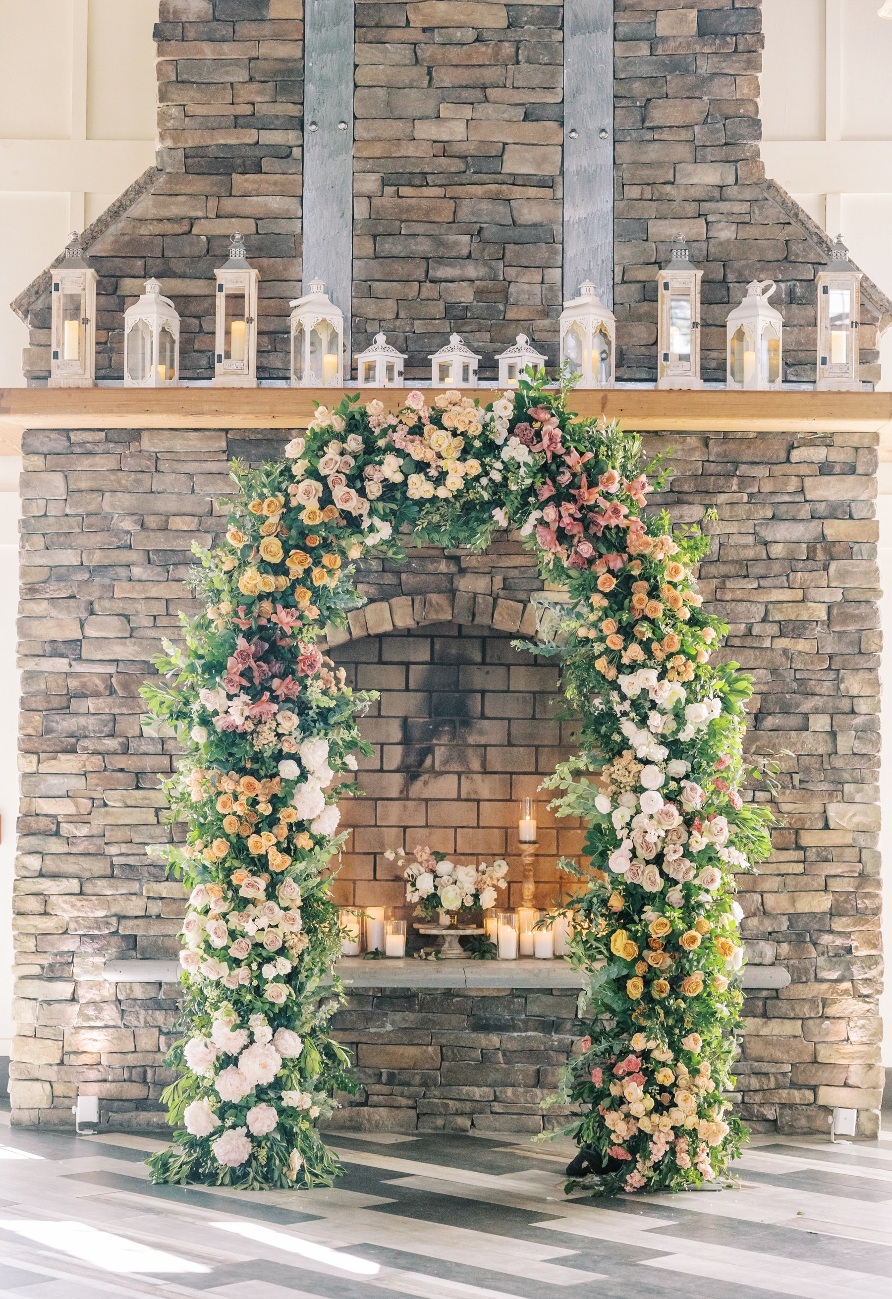 Wedding flower arch with pink, orange, and blush roses by Twisted Willow Flowers