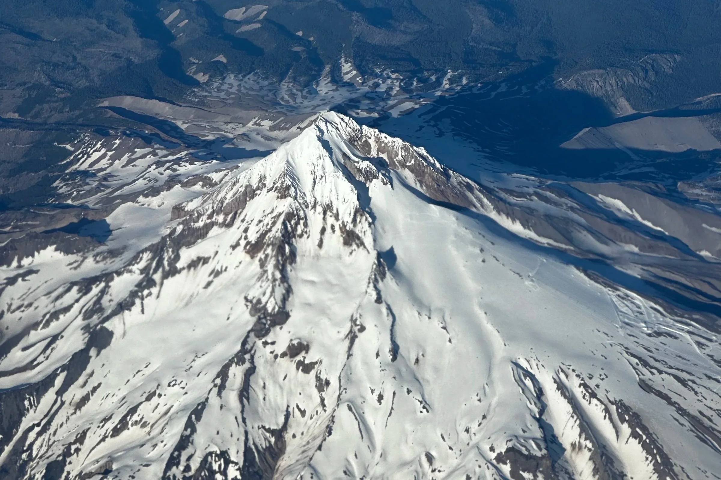 Aerial view of Mount St. Helens with snow-covered summit and surrounding landscape in Washington state.
