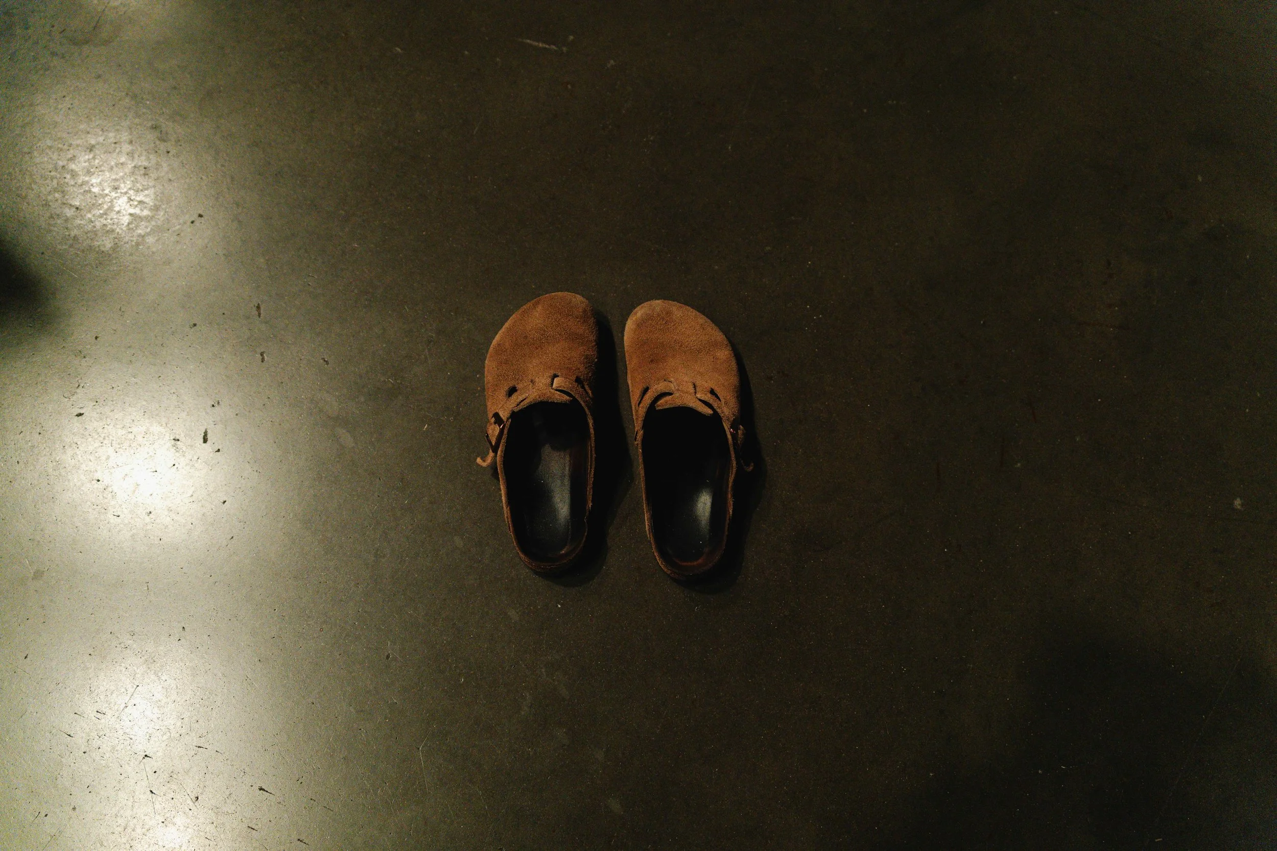 A pair of brown shoes on a dark, smooth floor.