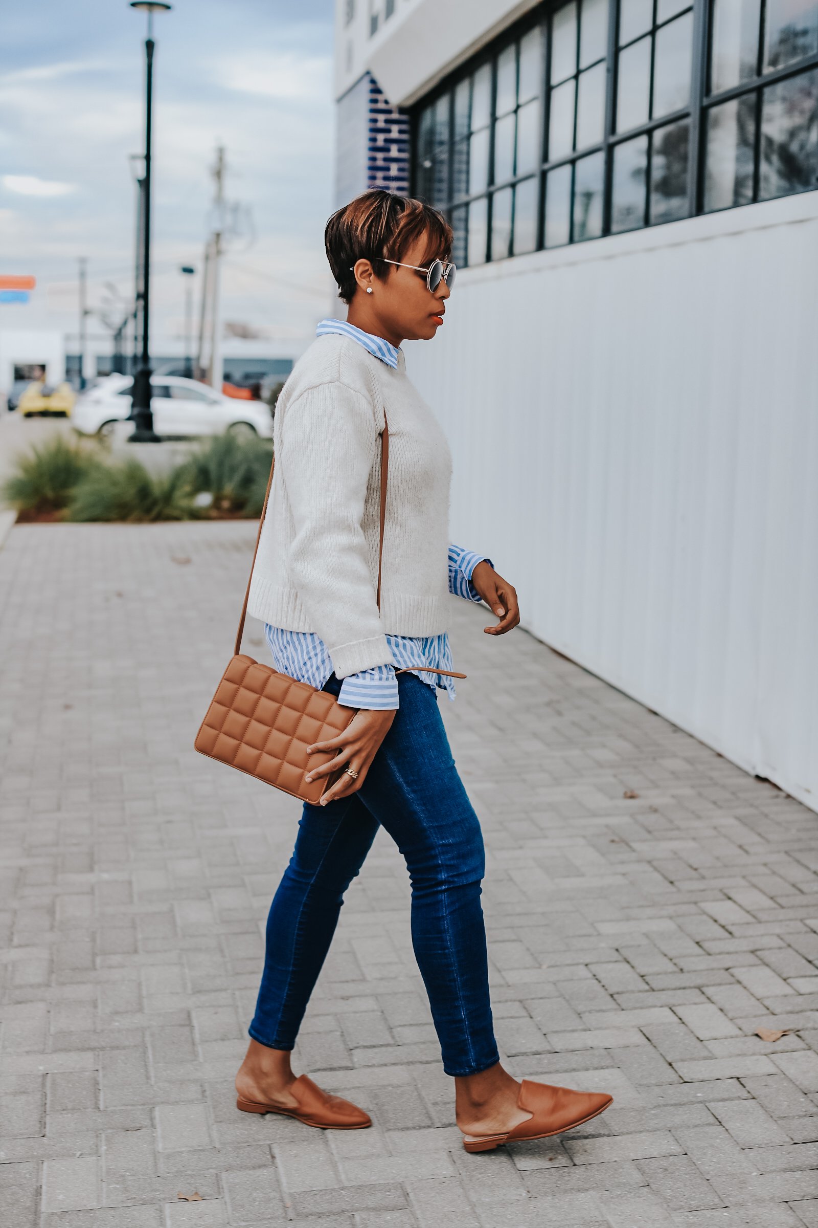 Mary's Little Way in A White Crewneck Sweater, a Blue and White Striped Boyfriend Shirt, Blue Jeans, and Tan Mules