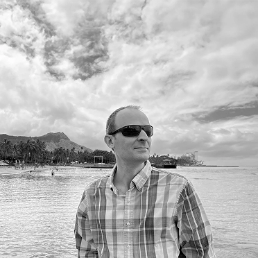 Black and white photo of Luke Pieczynski wearing sunglasses and a button down shirt outdoors in Honolulu, Hawaii