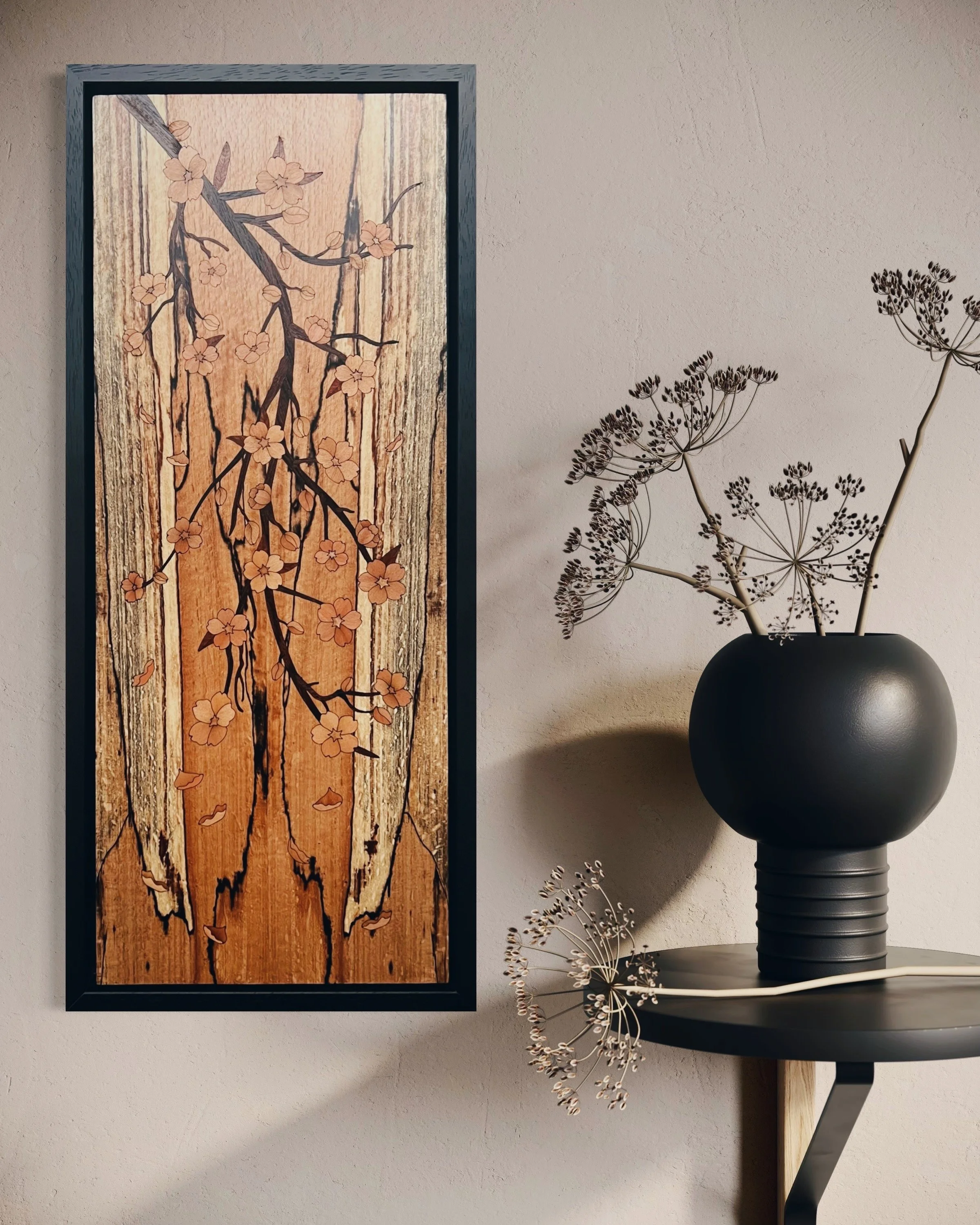 Decorative marquetry wall art featuring a cherry blossom tree on a wooden background, next to a black vase with dried flowers on a shelf. Created by Carl Fox