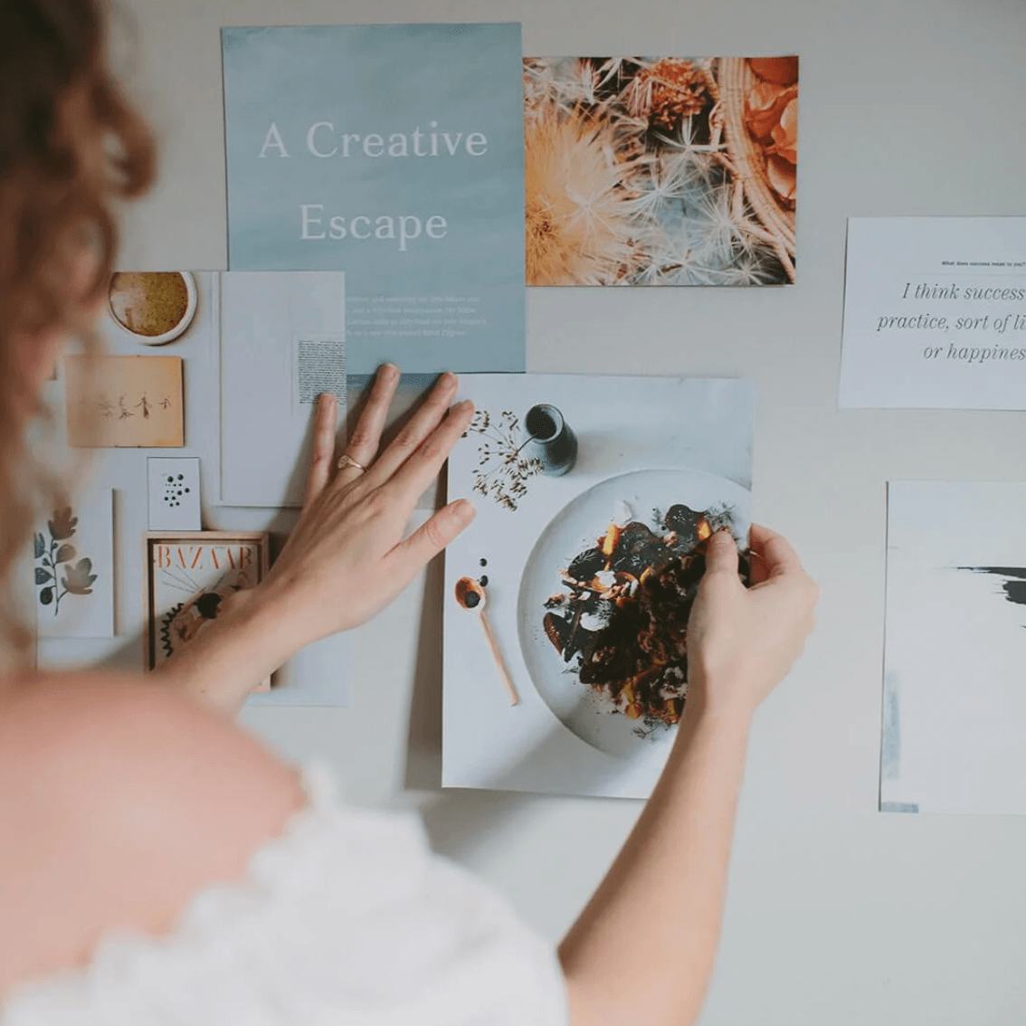 Image of woman over her shoulder creating photos on a wall hanging moodboard