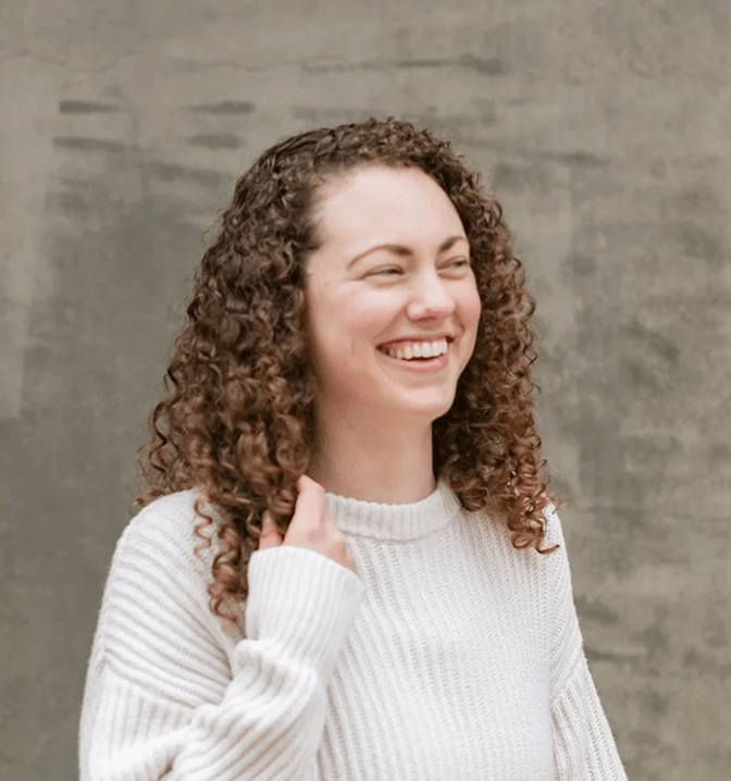 Woman and female with curly hair smiling happy who is a an SEO Coach
