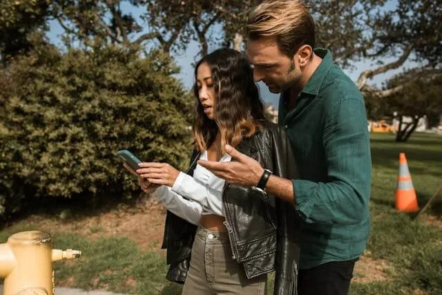 Man hovering over woman’s phone in a controlling way, showing possessiveness and trust issues — relationship counseling in Bellaire, Texas.