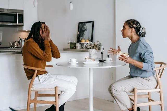 Man holding his head in frustration during an argument while partner tries to explain, showing poor communication — Bellaire couples therapy.