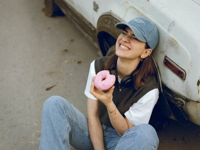 Image of a woman happily eating a doughnut, representing the idea that finding delight is a skill that grows with practice. Wilson Counseling encourages cultivating this mindset for a healthier life.