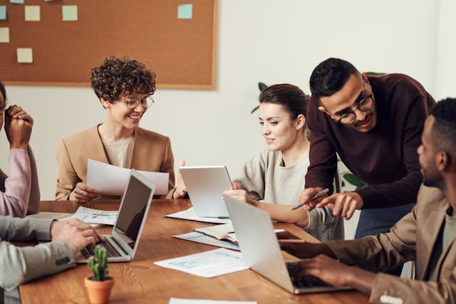 Group of coworkers smiling in a meeting, showing reduced workplace stress and improved communication supported by CBT at Wilson Counseling in Houston.